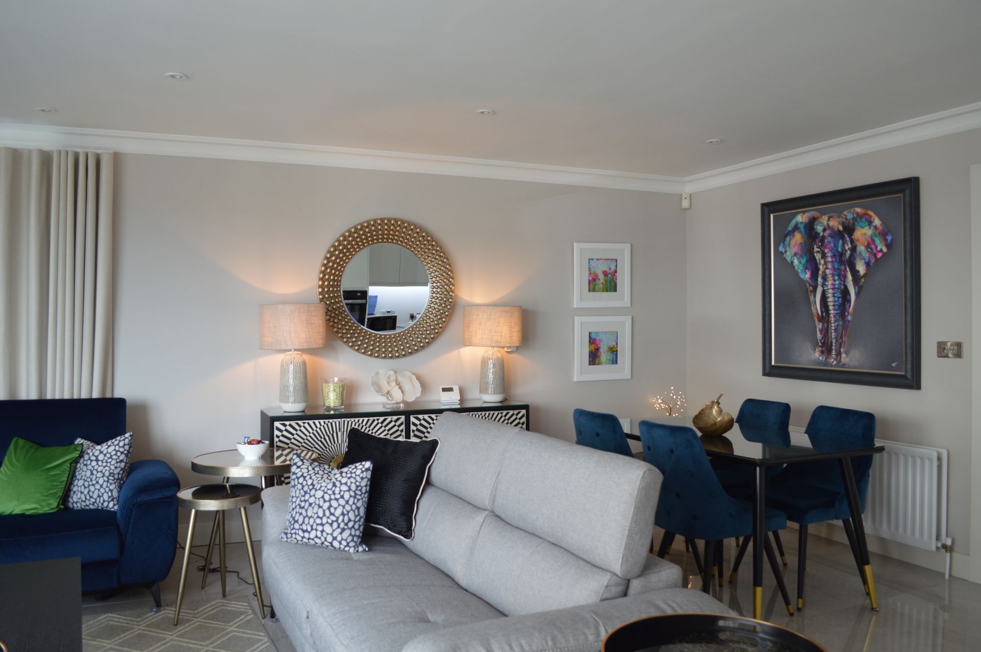 A living room with a couch , chairs , a table and a mirror.