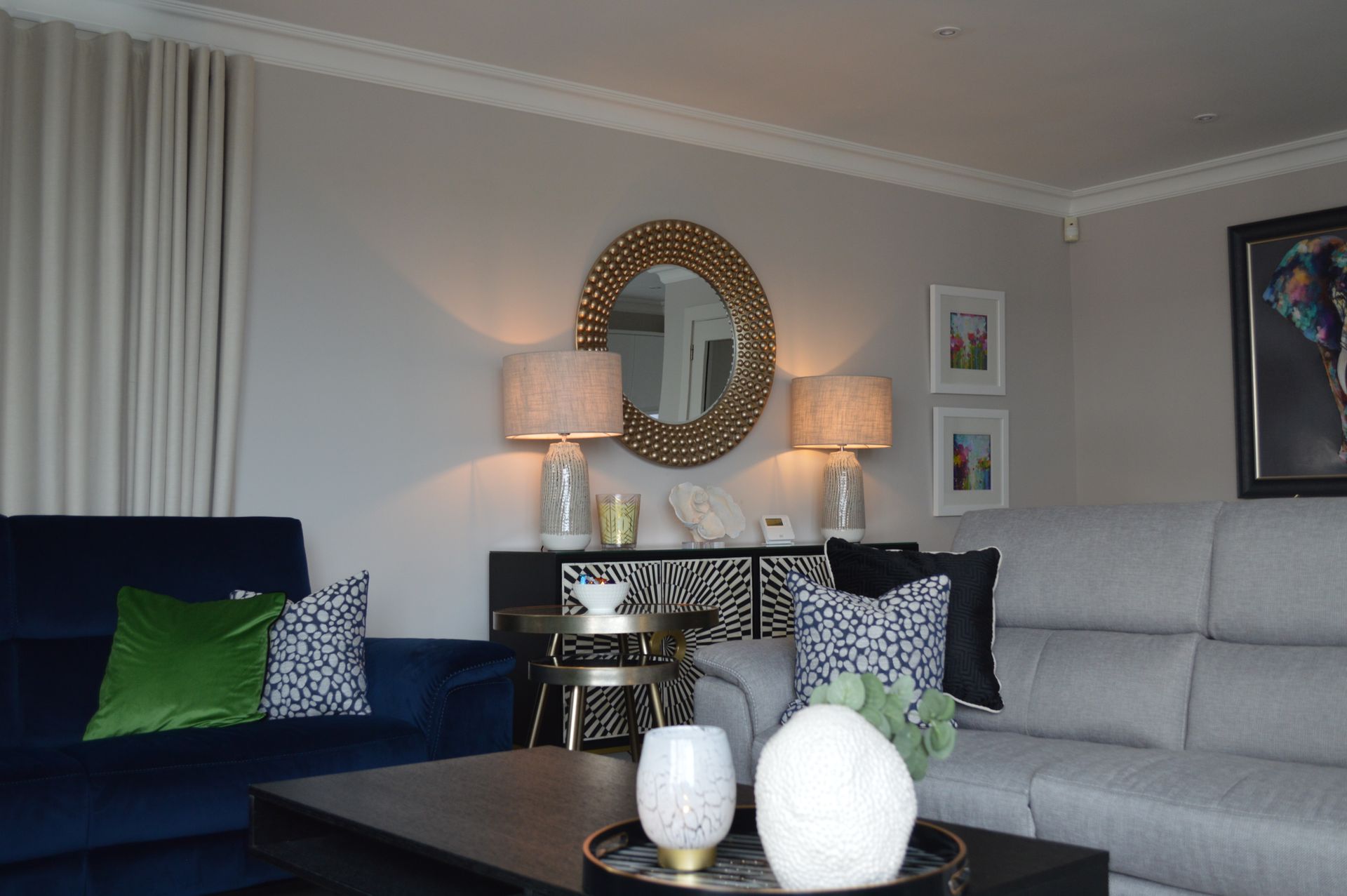 A living room with a couch , table , lamps and a mirror.