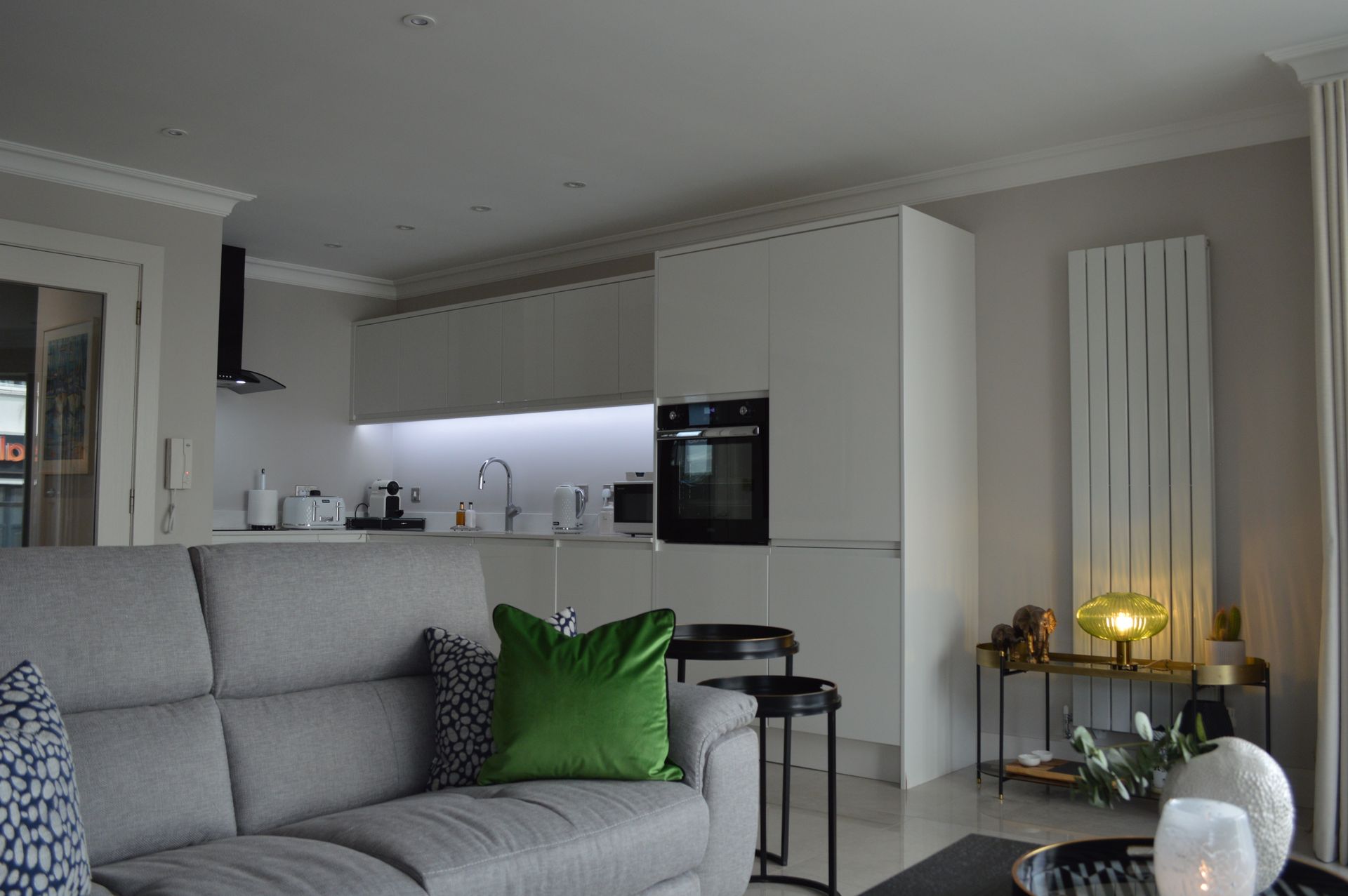 A living room with a gray couch and a green pillow.