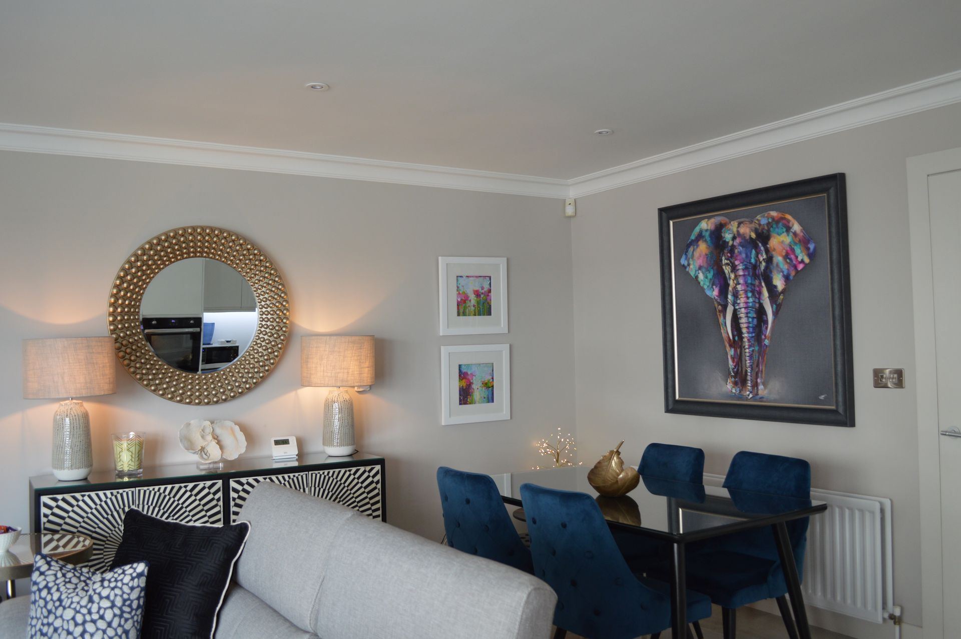 A living room with a couch , table and chairs and a painting of an elephant on the wall.