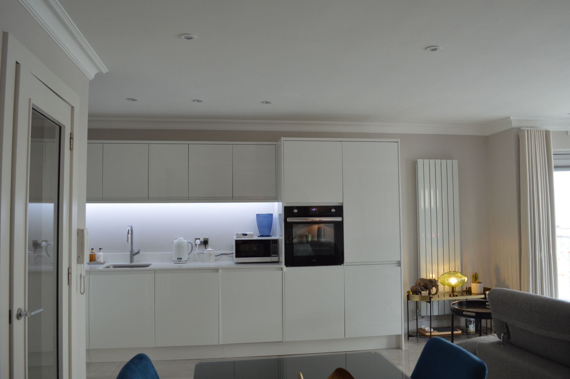 A kitchen with white cabinets , a stove , a microwave , and a sink.