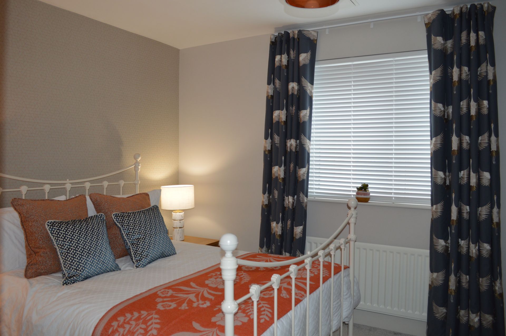 A bedroom with a bed and a window with blinds.