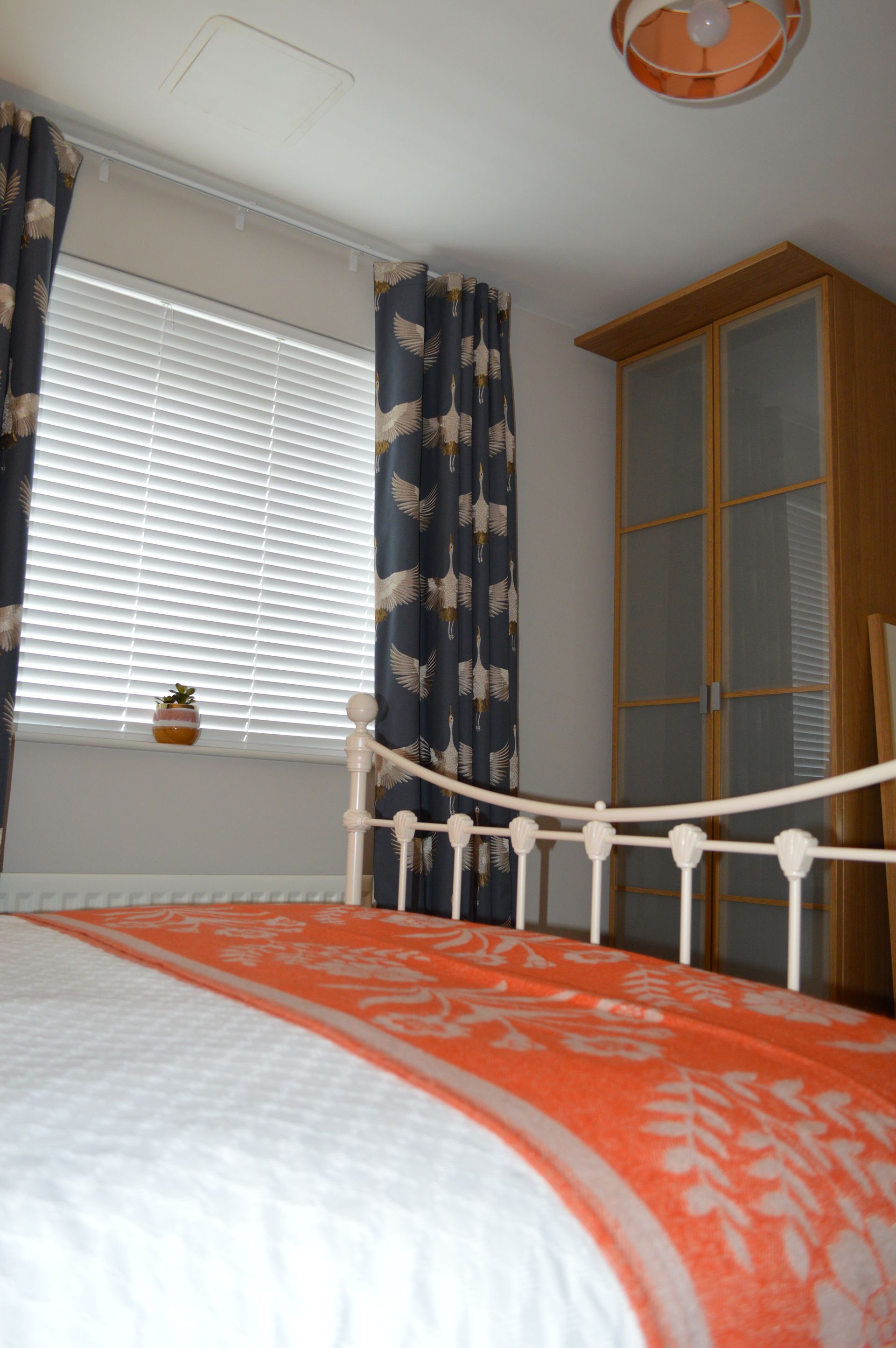 A bedroom with a bed and a window with blinds