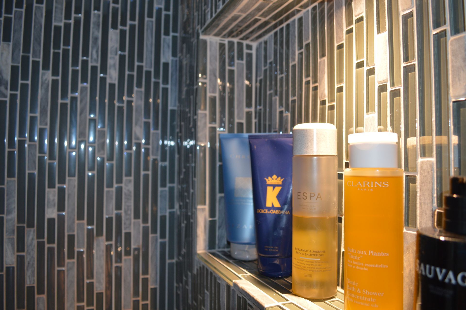 Three bottles of lotion are on a shelf in a bathroom