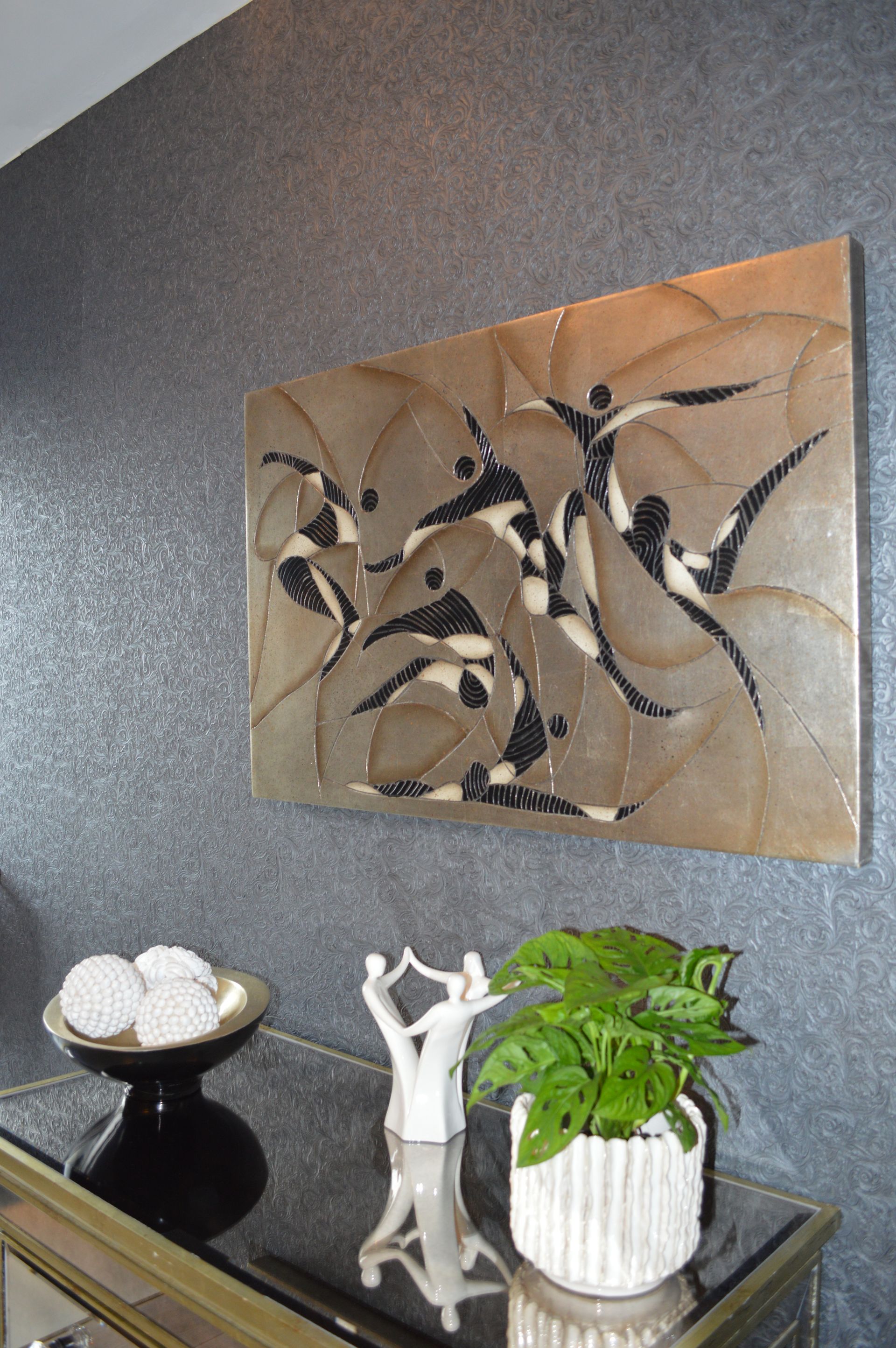 A table with a plant and a painting on the wall