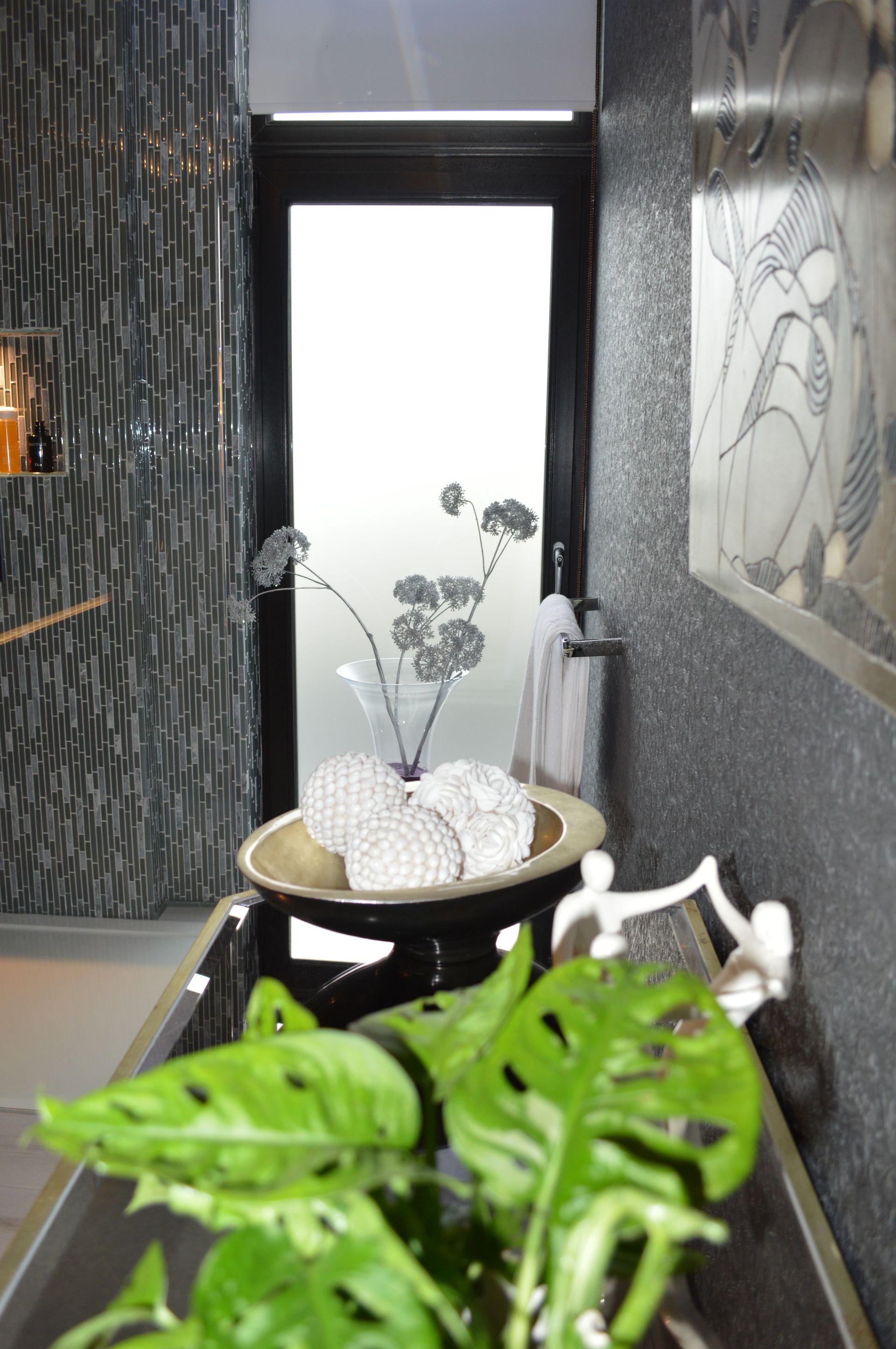 A bathroom with a plant in front of a glass door
