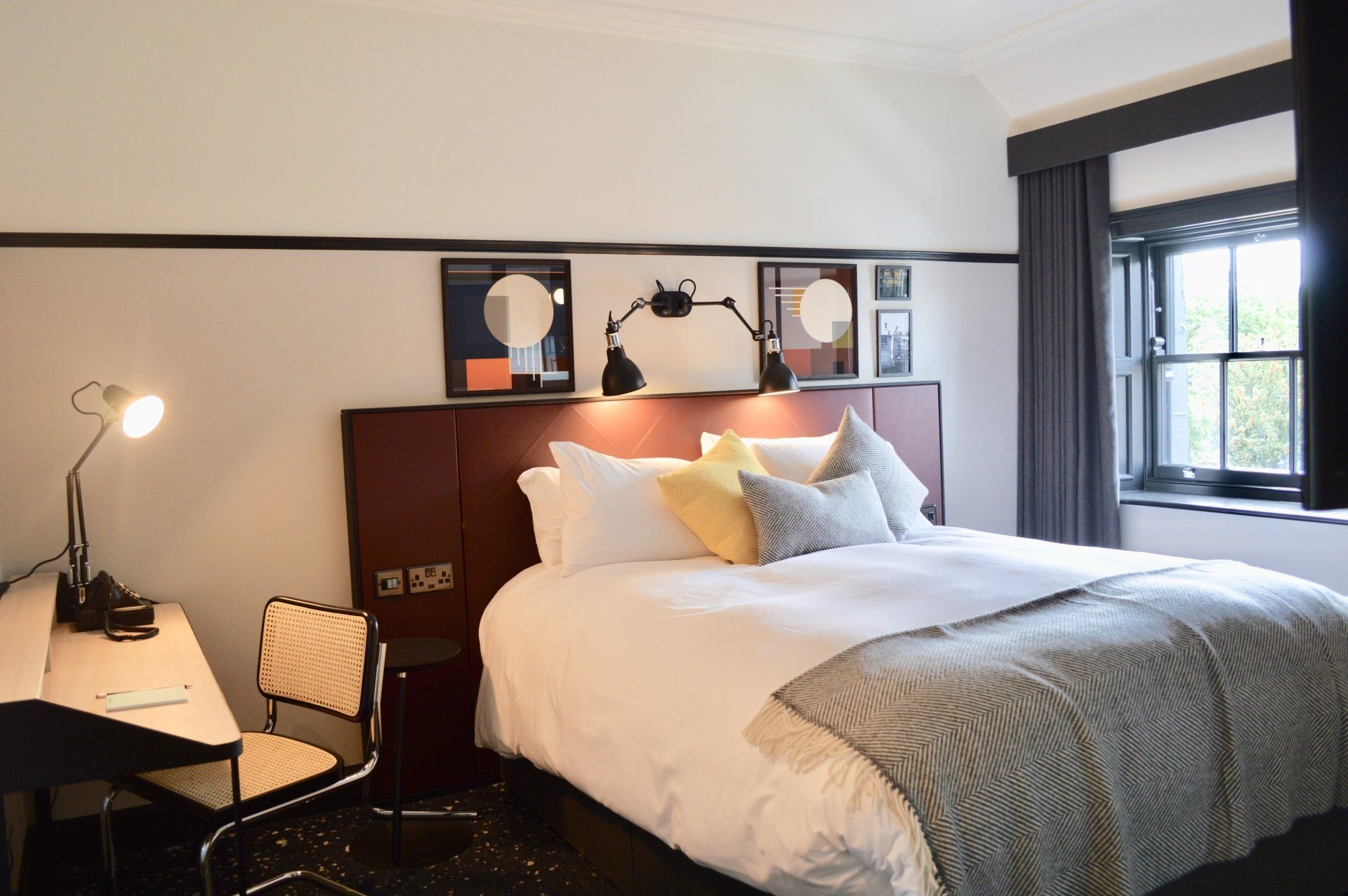A hotel room with a large bed , desk and chair.
