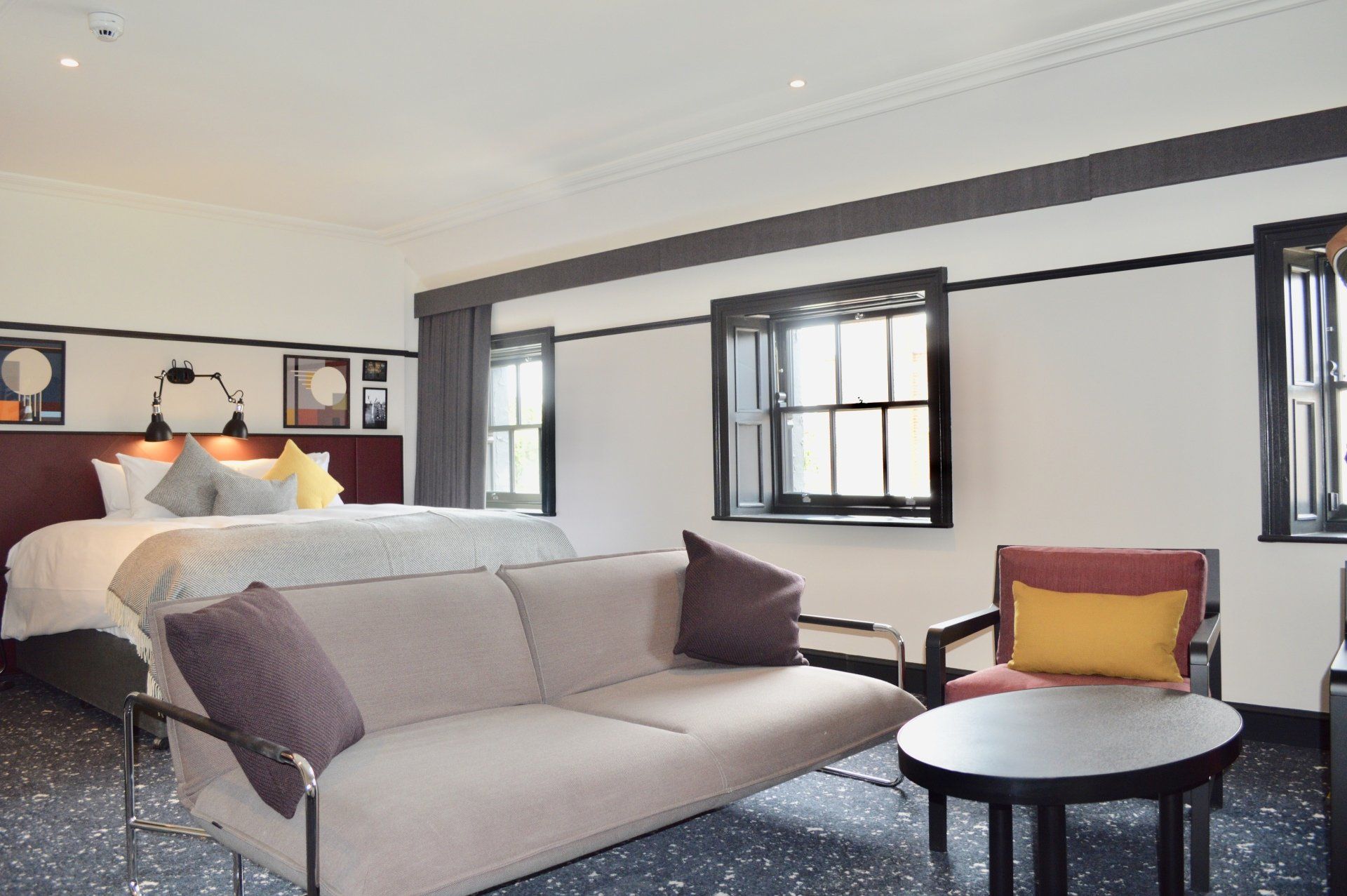 A hotel room with a couch , chair , table and bed.