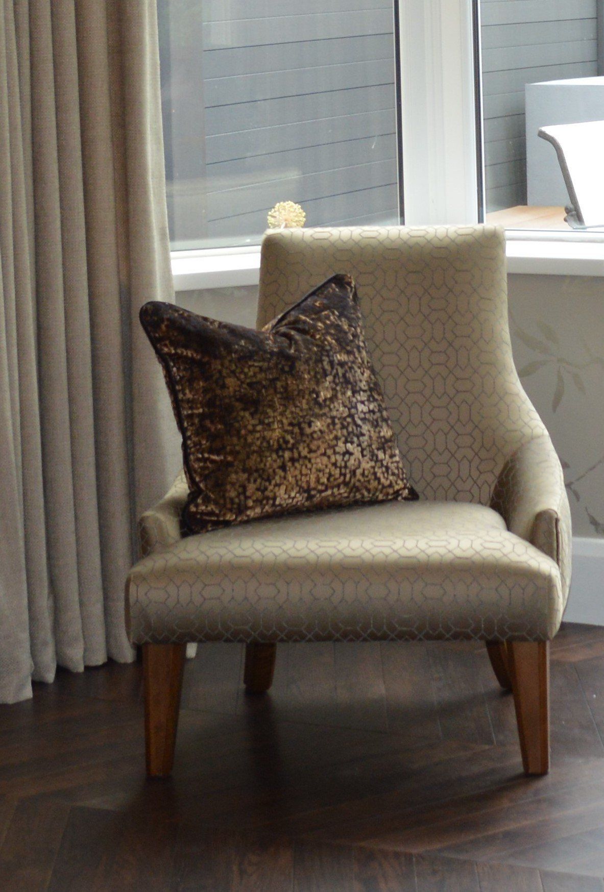 A chair with a pillow on it in front of a window.