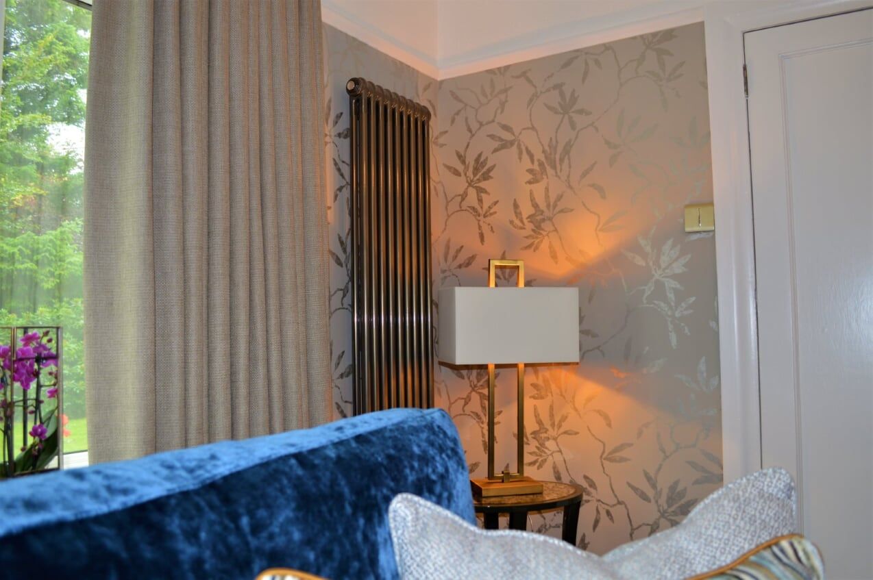 A living room with a blue couch , a lamp , and a window.