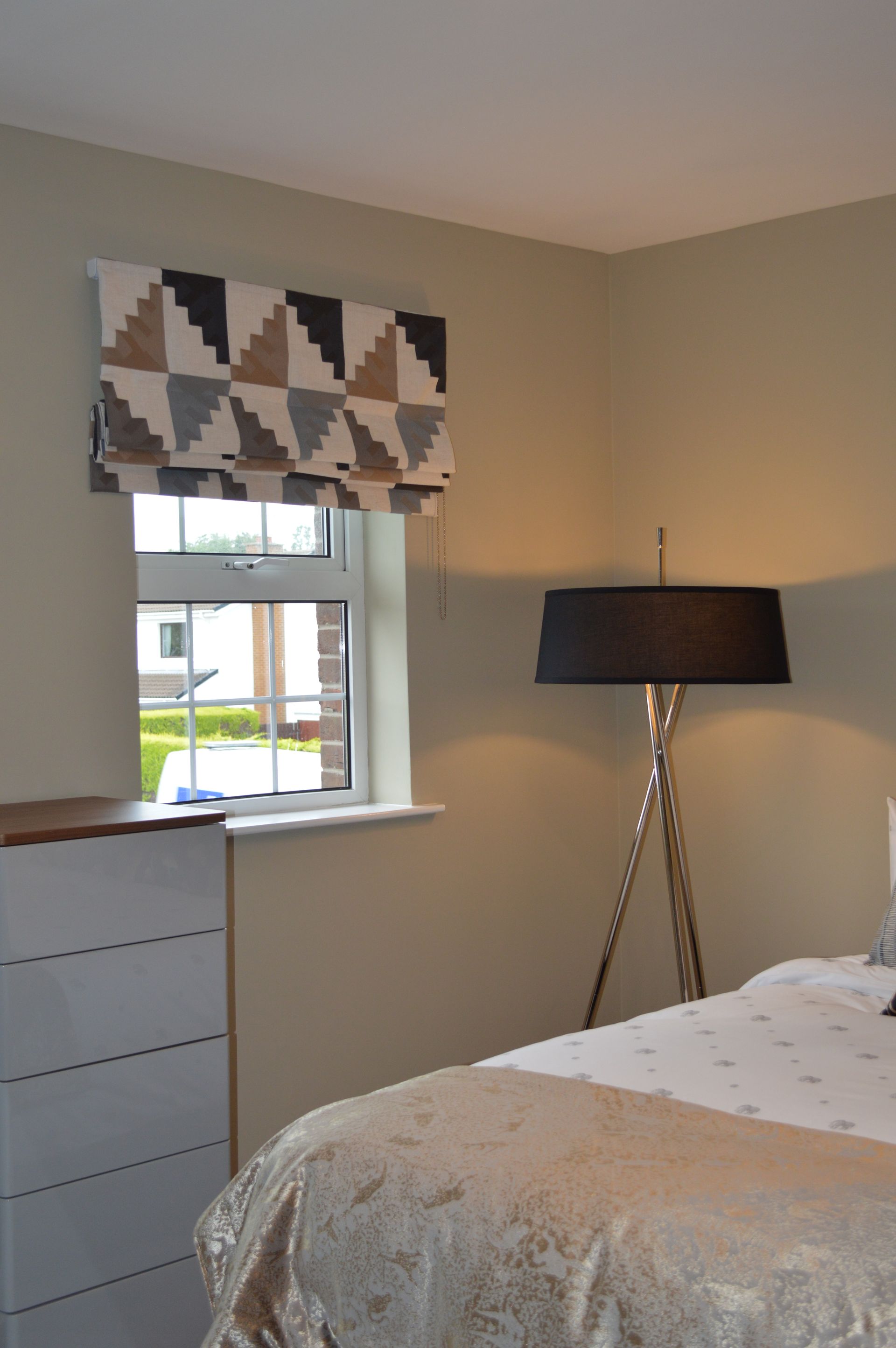 A bedroom with a bed a lamp and a window