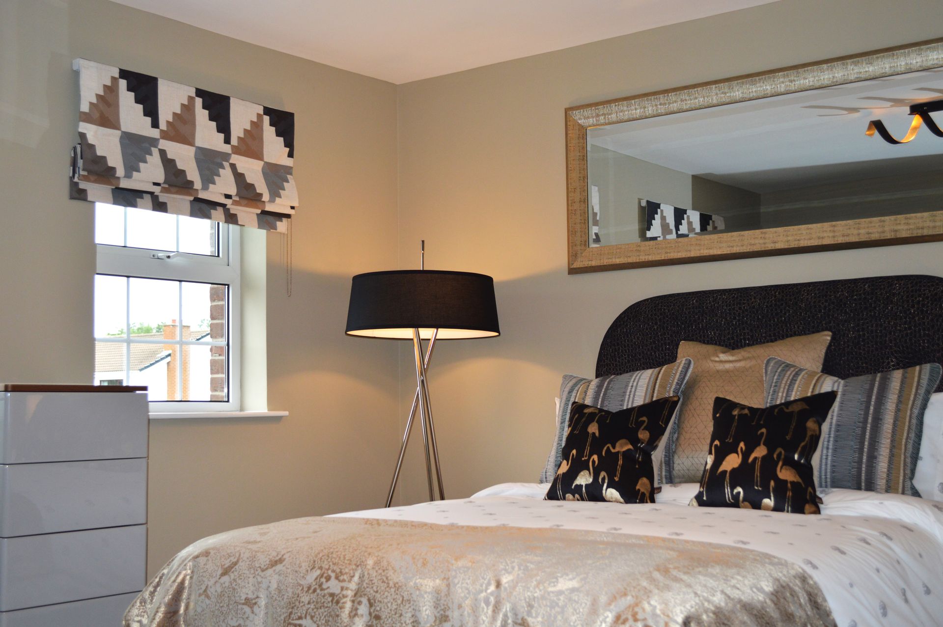 A bedroom with a bed , lamp , mirror and window