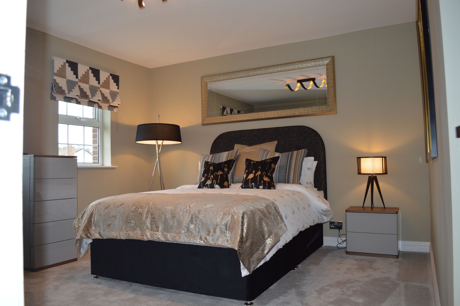 A bedroom with a bed , nightstand , lamp and mirror.