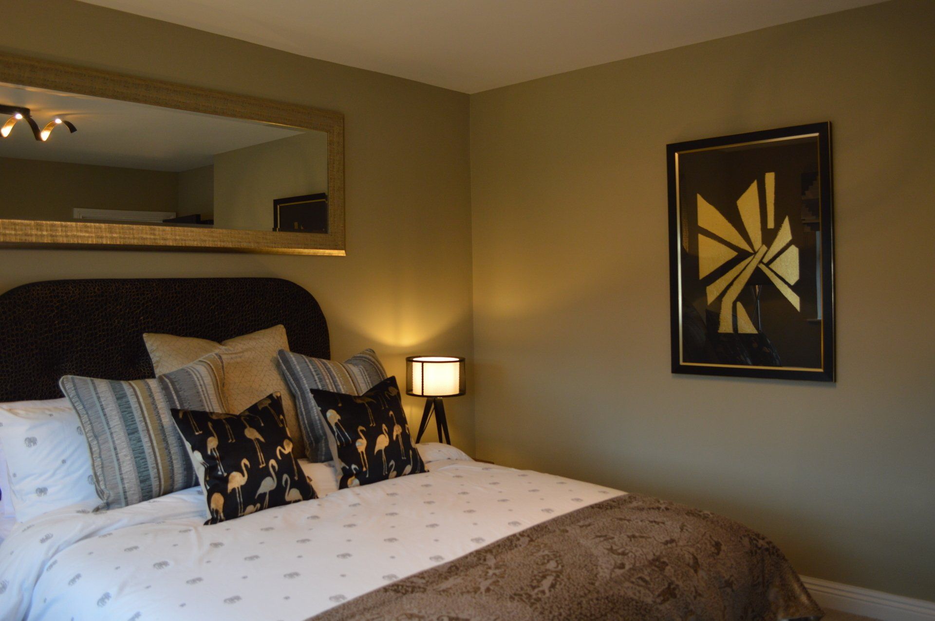 A bedroom with a large bed and a large mirror