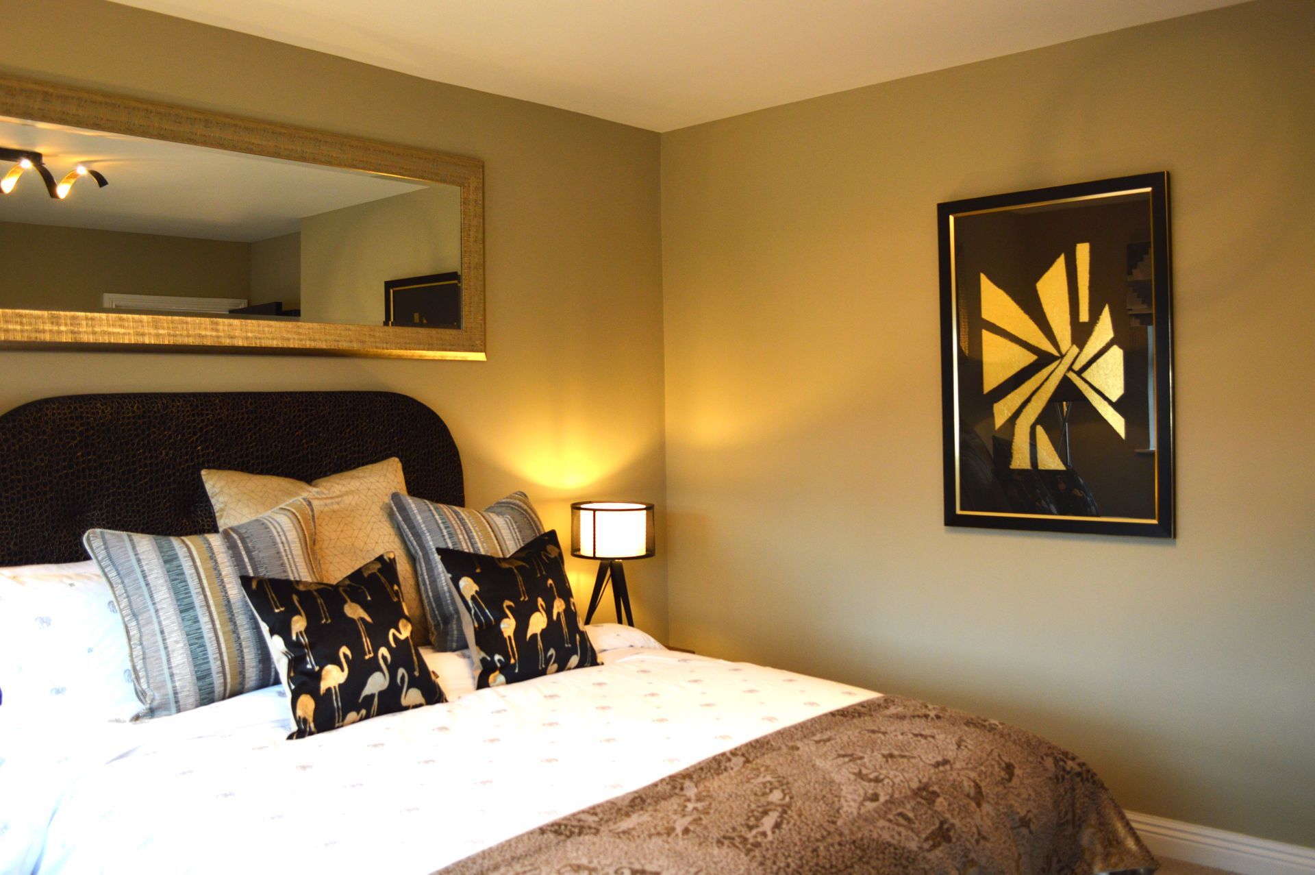 A bedroom with a large bed and a large mirror