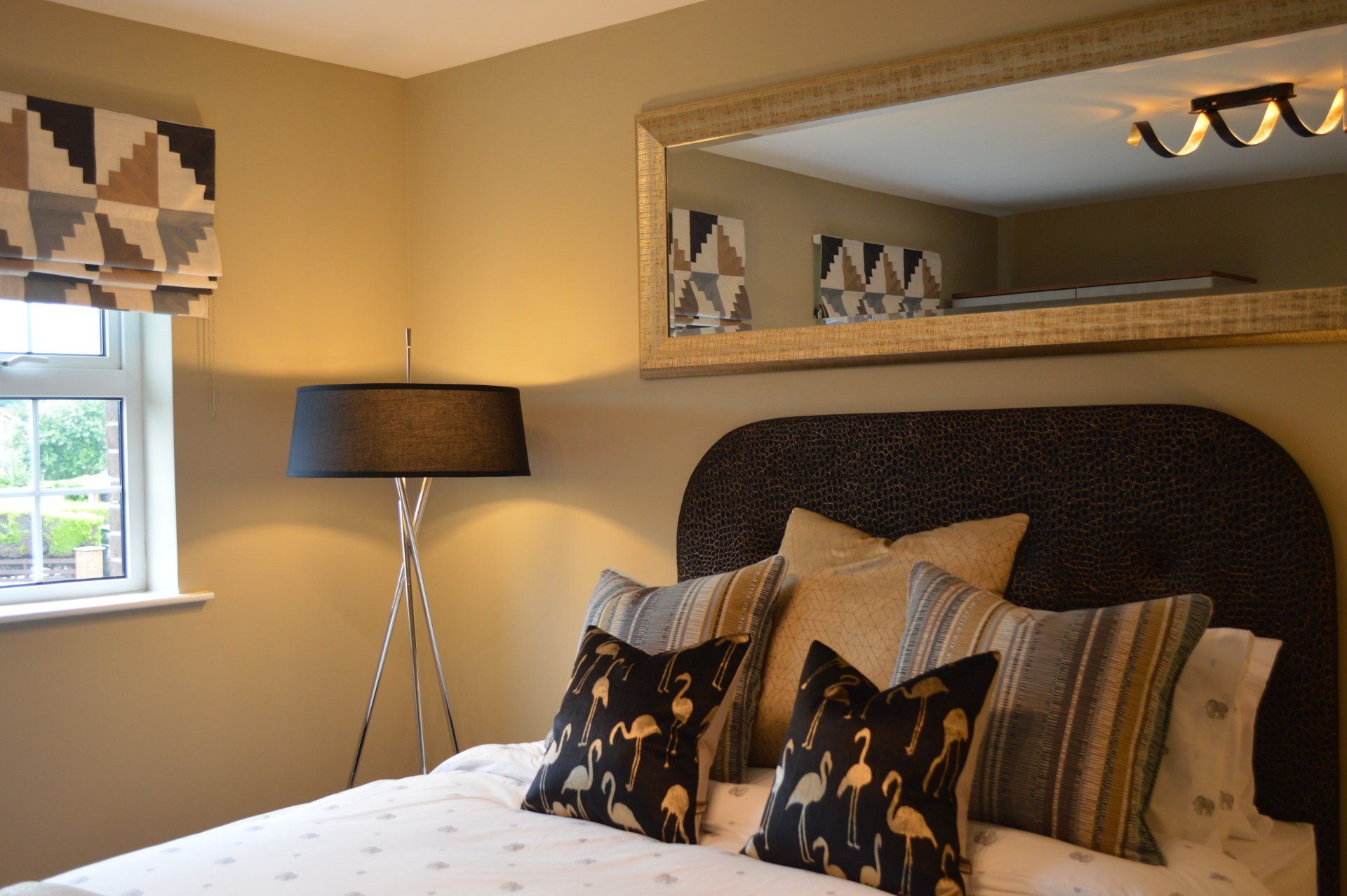 A bedroom with a large mirror above the bed