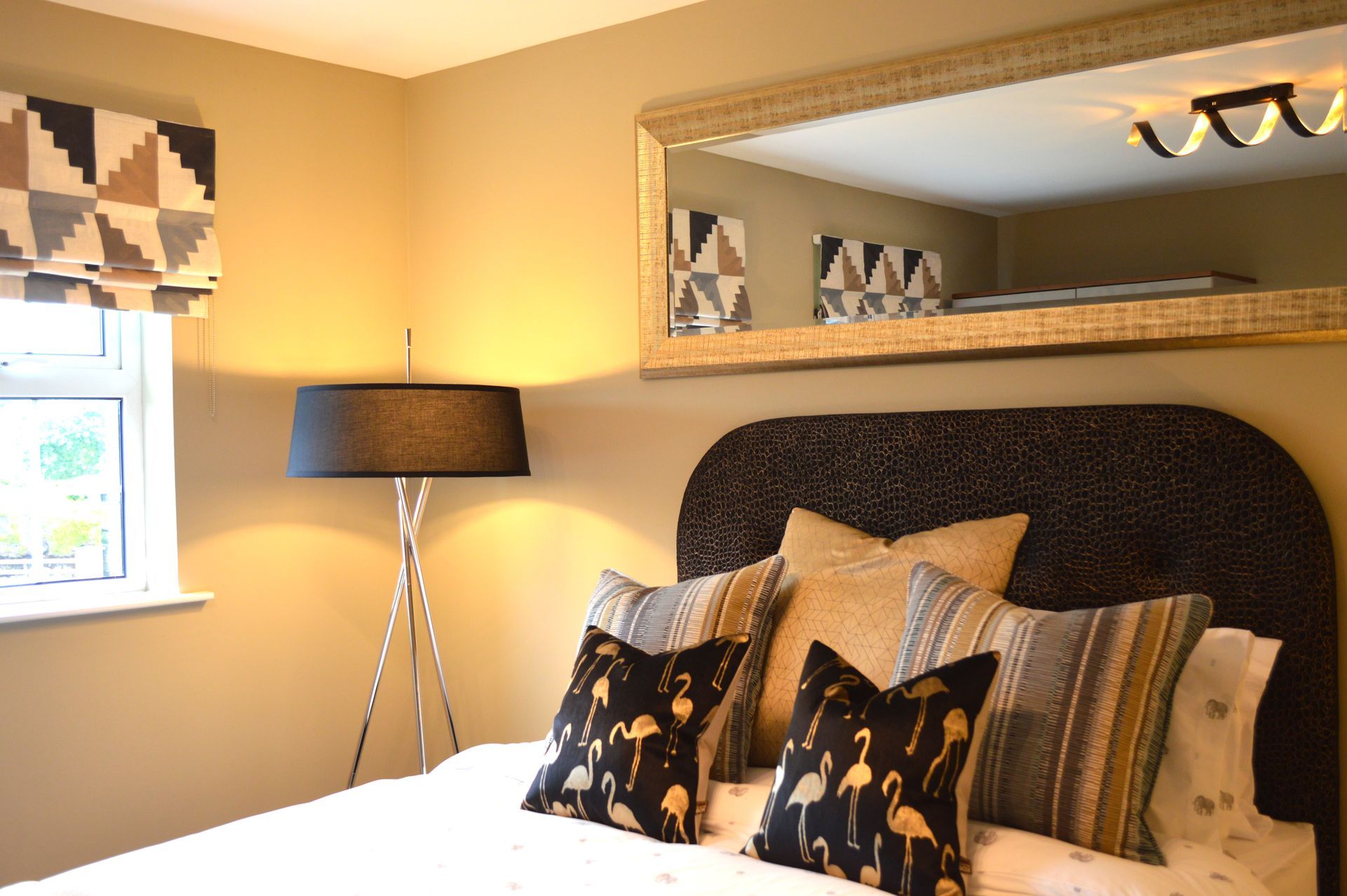 A bedroom with a large mirror above the bed