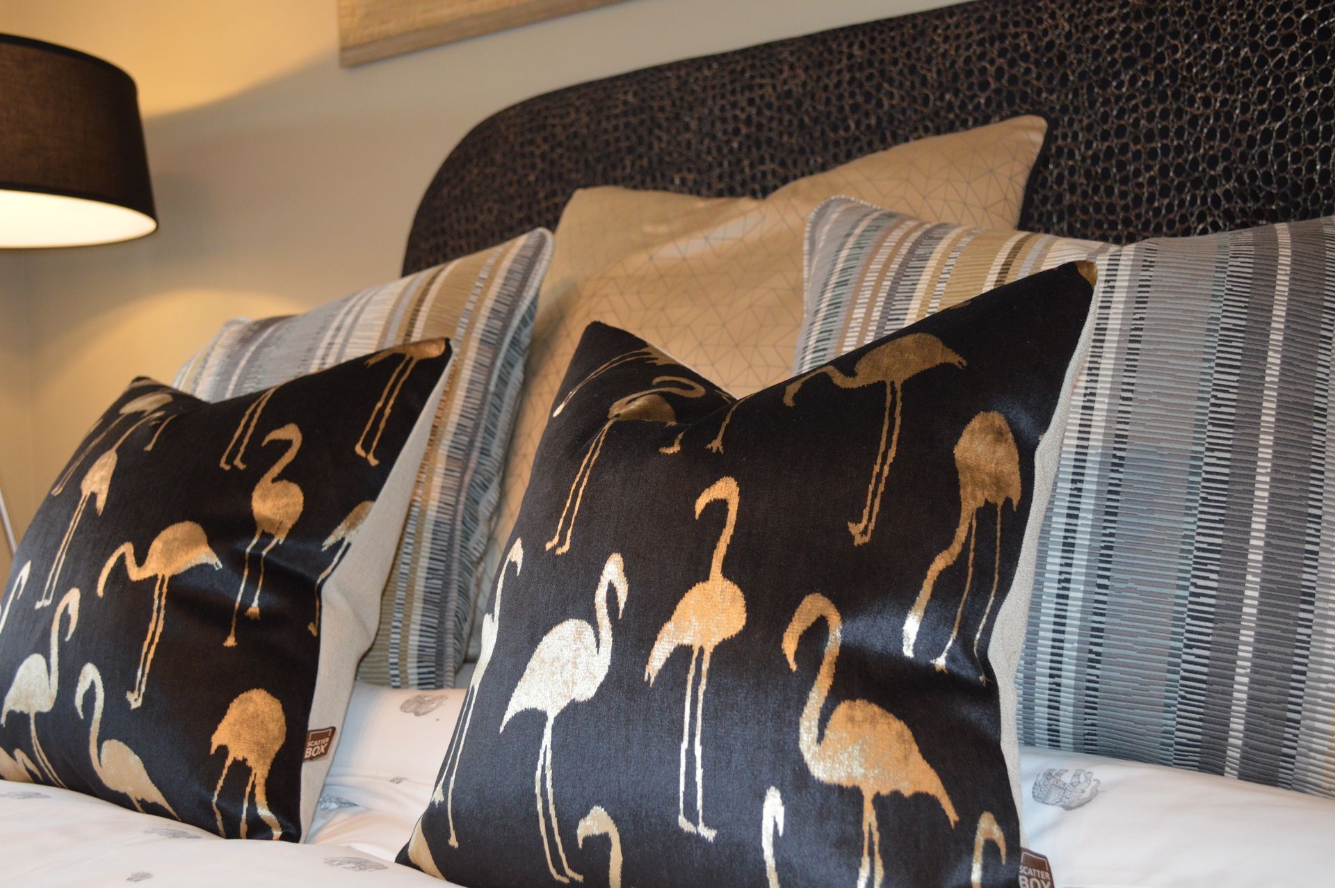 A bed with a lamp and pillows with flamingos on them