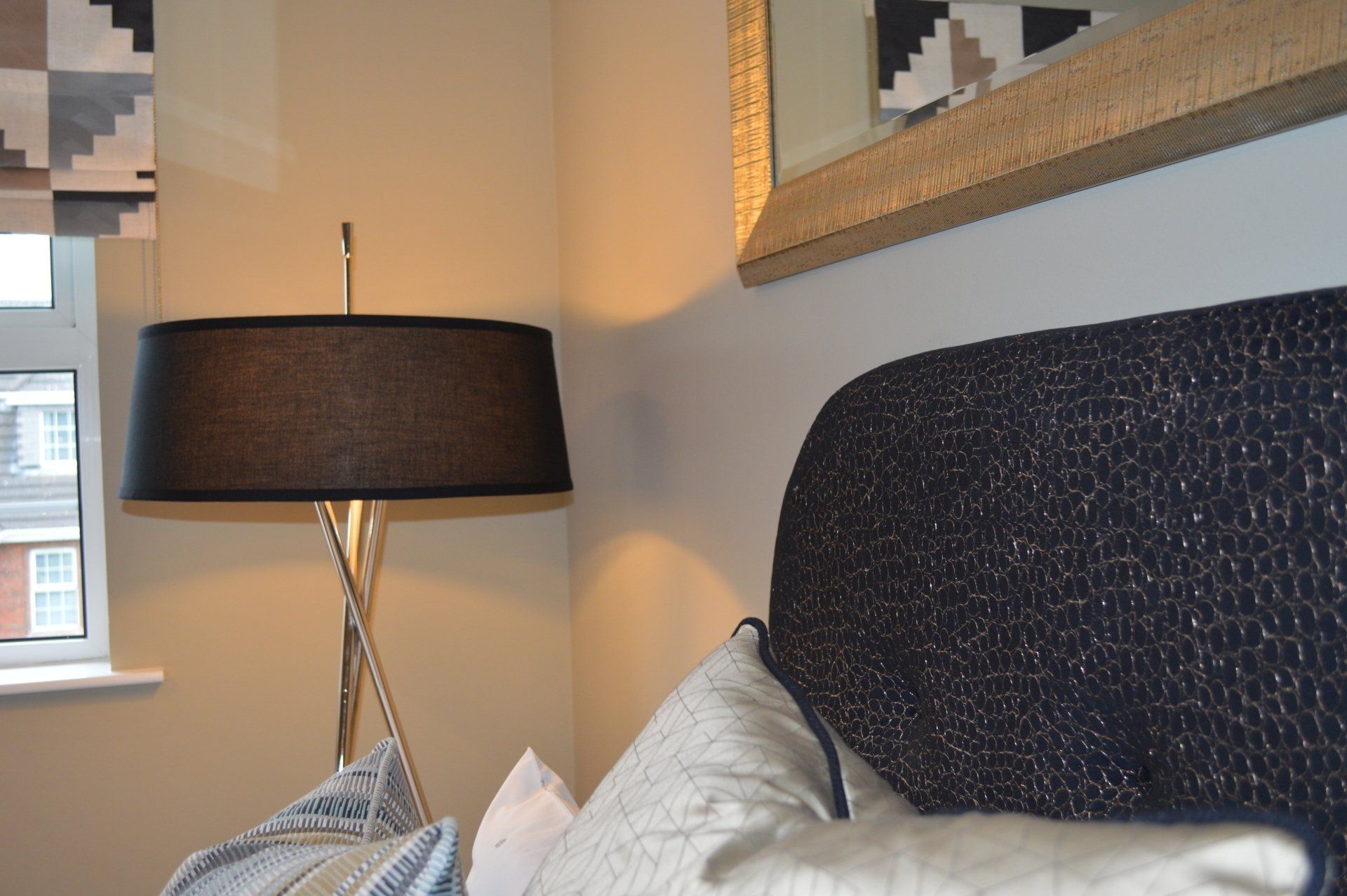 A bedroom with a bed a lamp and a mirror