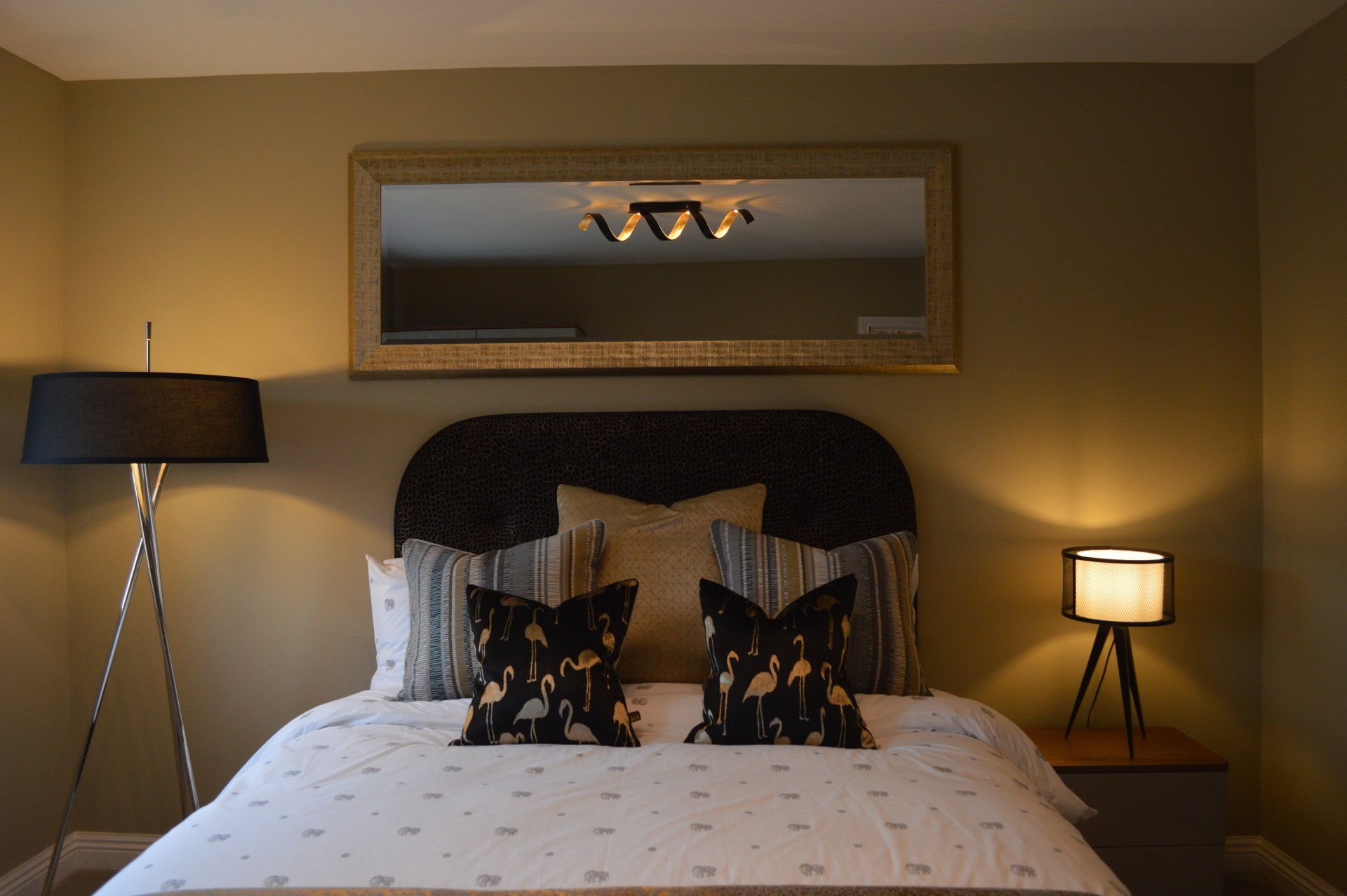 A bedroom with a bed , lamp and mirror