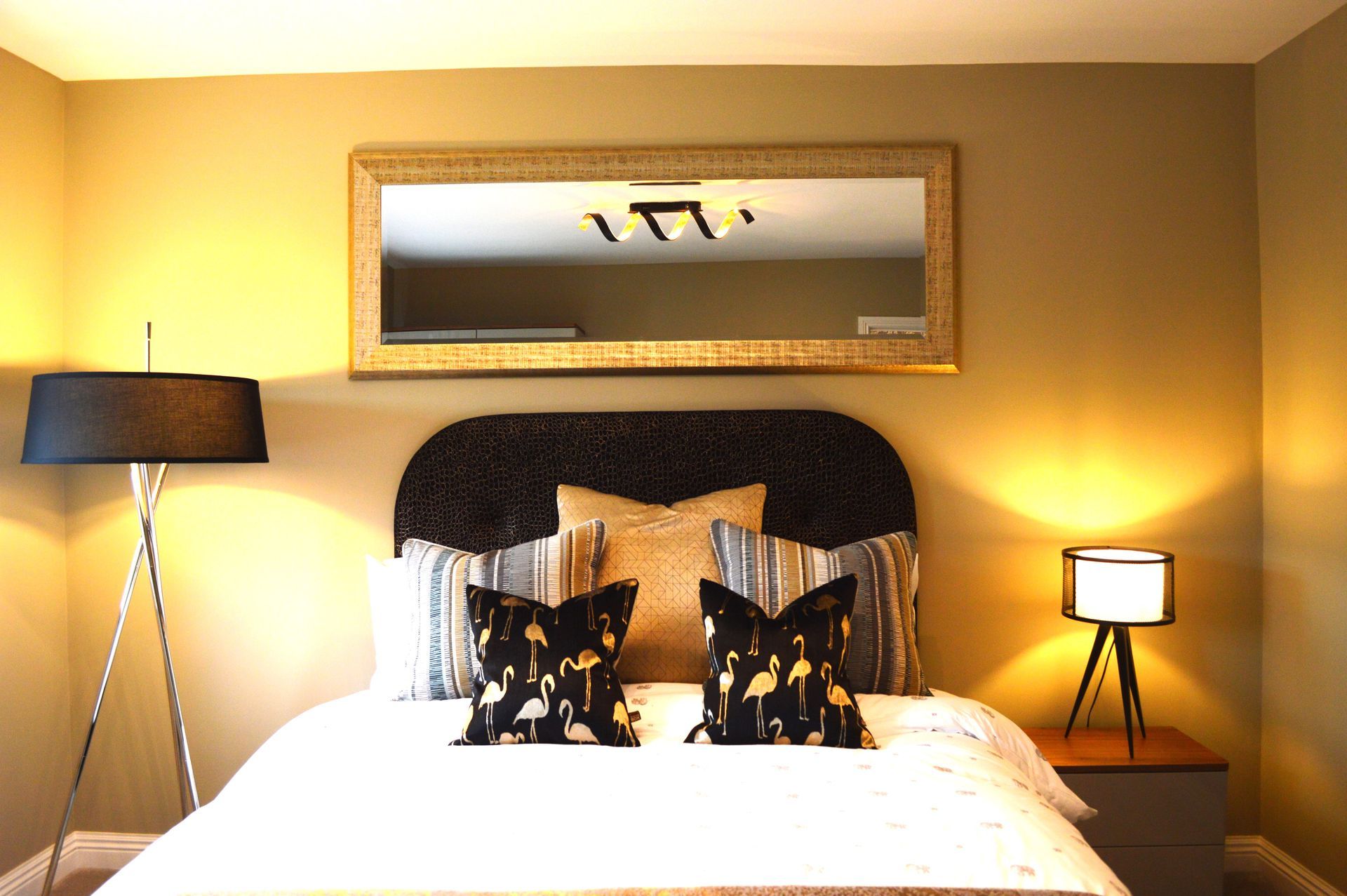 A bedroom with a large mirror above the bed