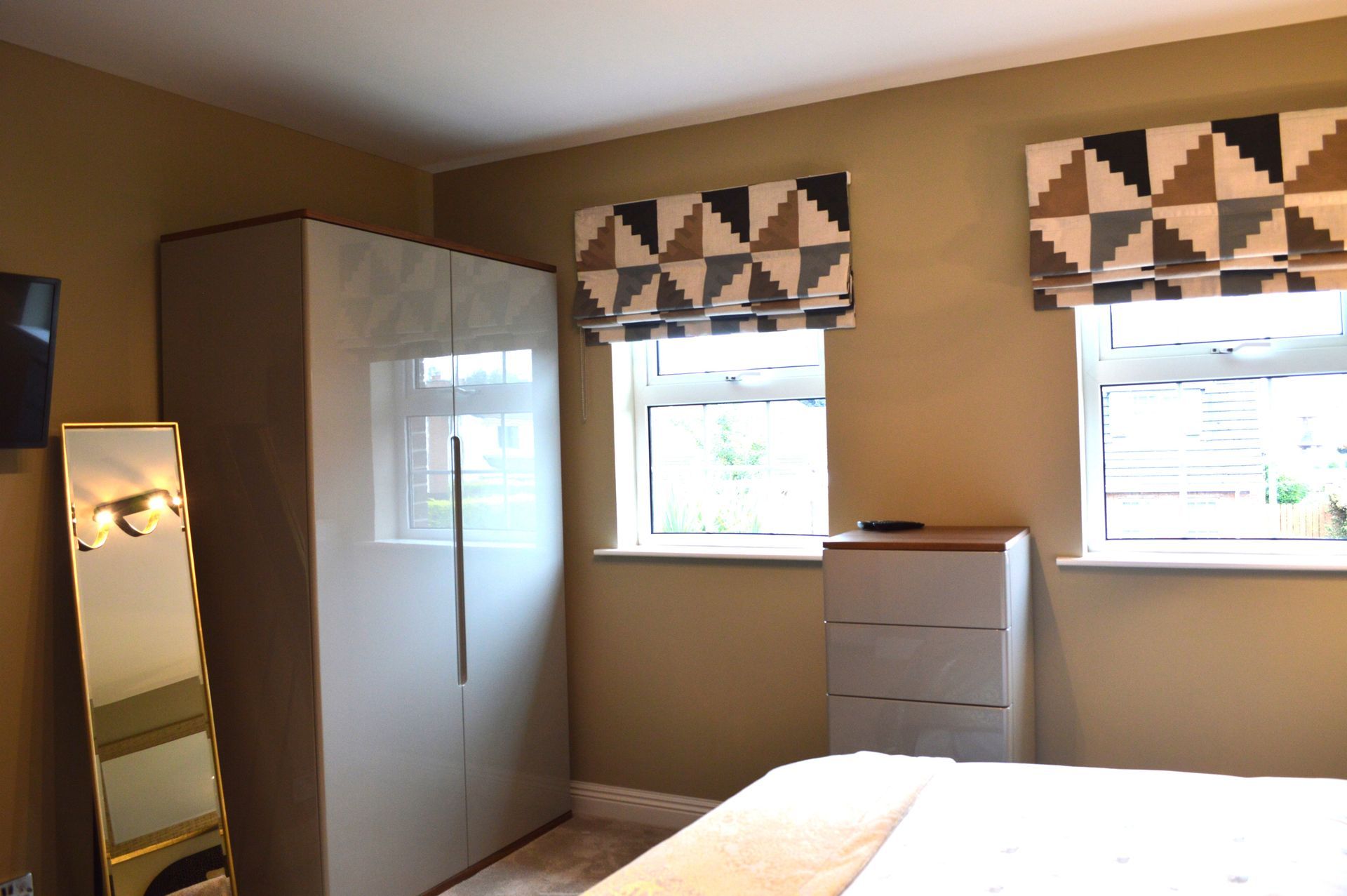 A bedroom with a bed a mirror and a wardrobe