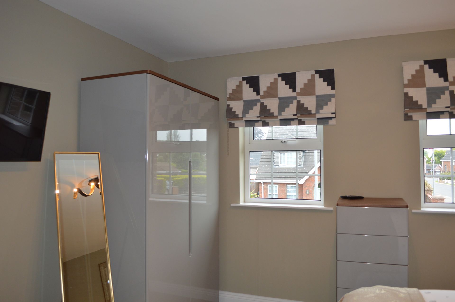 A bedroom with a bed , dresser , mirror and television.