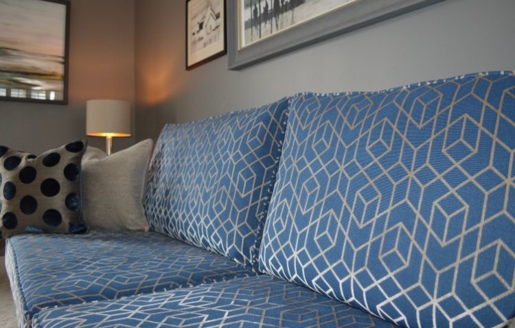 A blue couch with a pattern on it is in a living room.