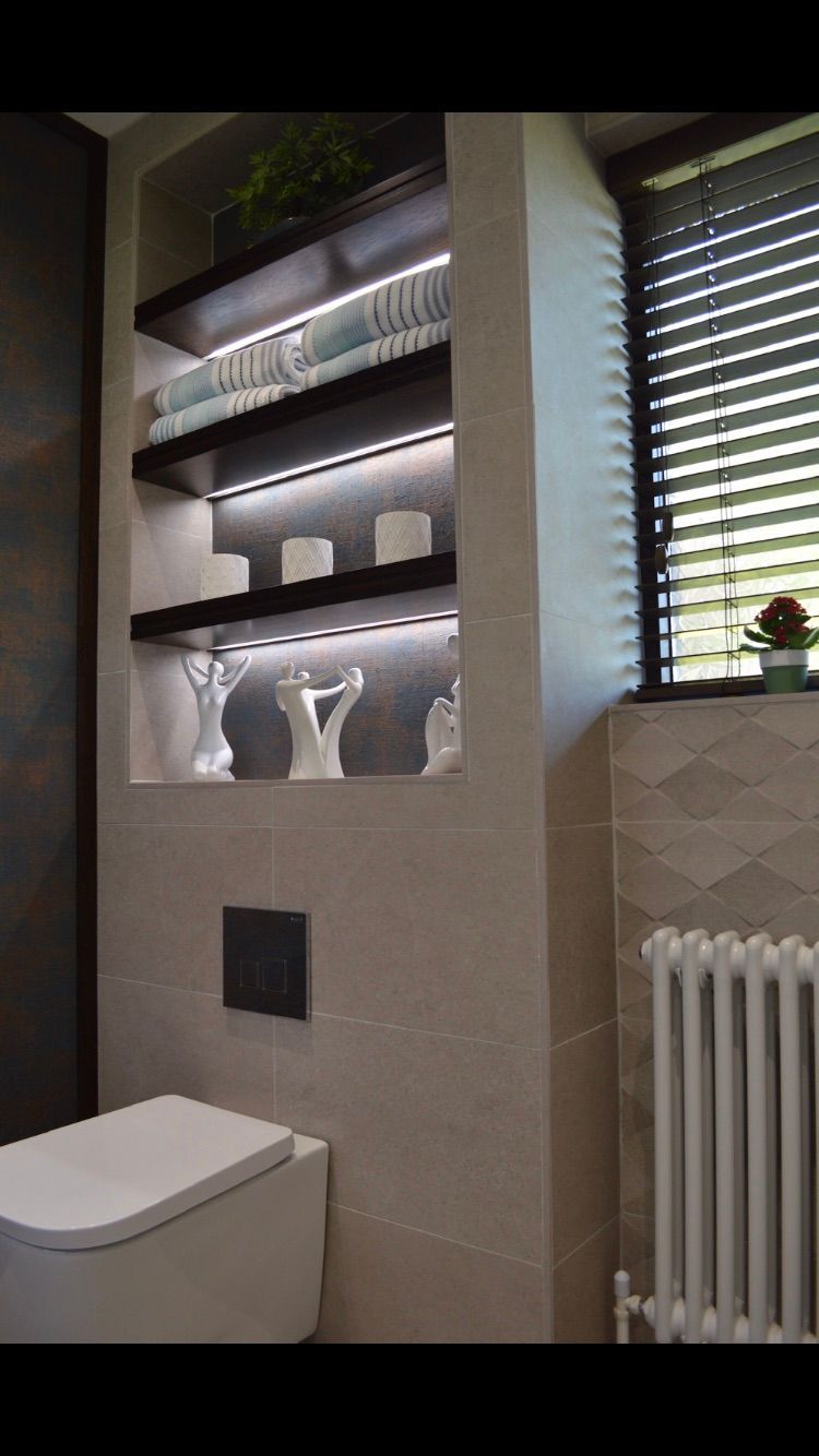 A bathroom with a toilet , shelves , and a radiator.