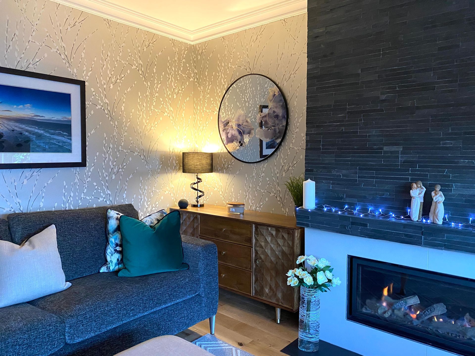 A living room with a couch , fireplace and mirror.