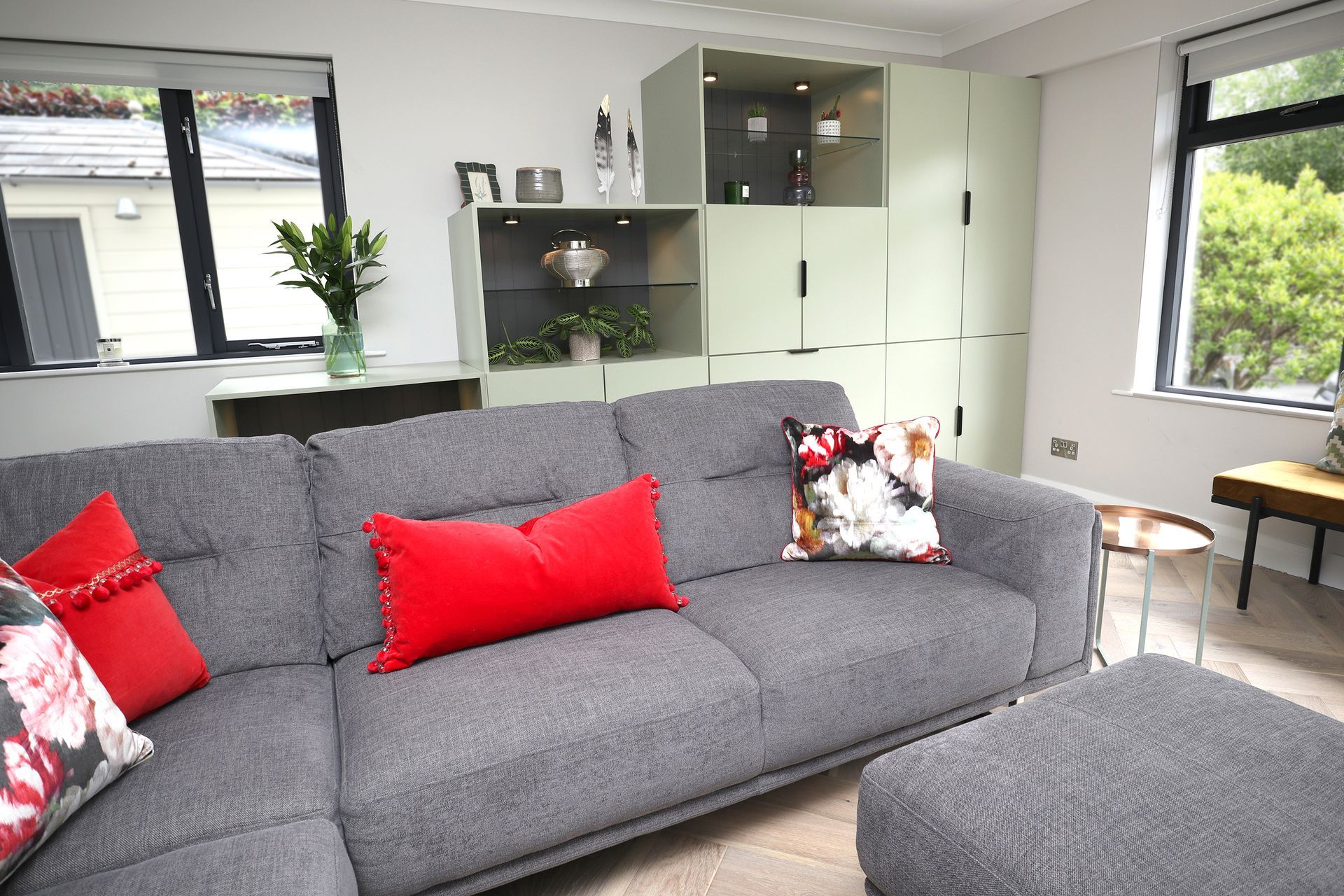 A living room with a grey couch and red pillows