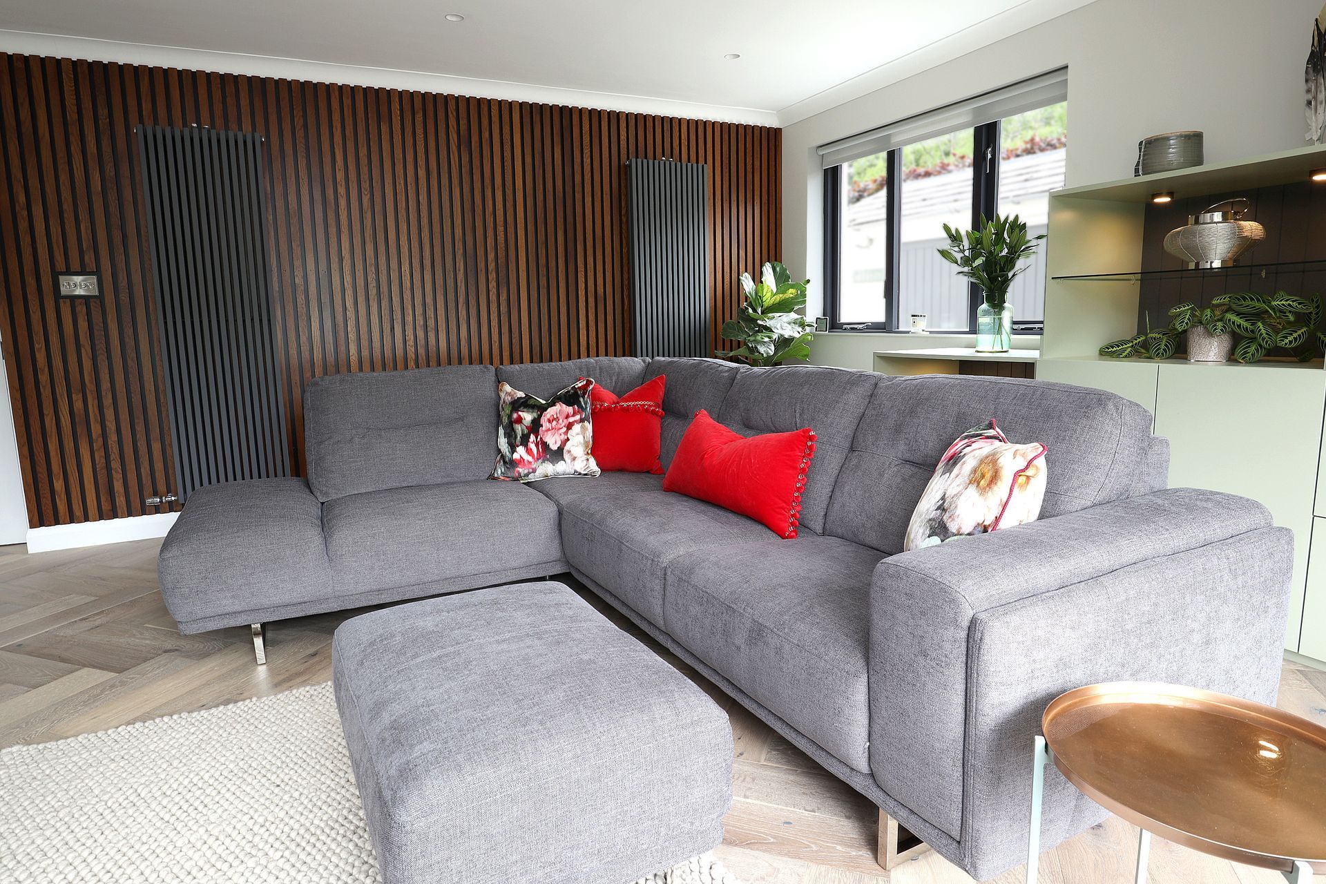 A living room with a gray sectional couch and red pillows.