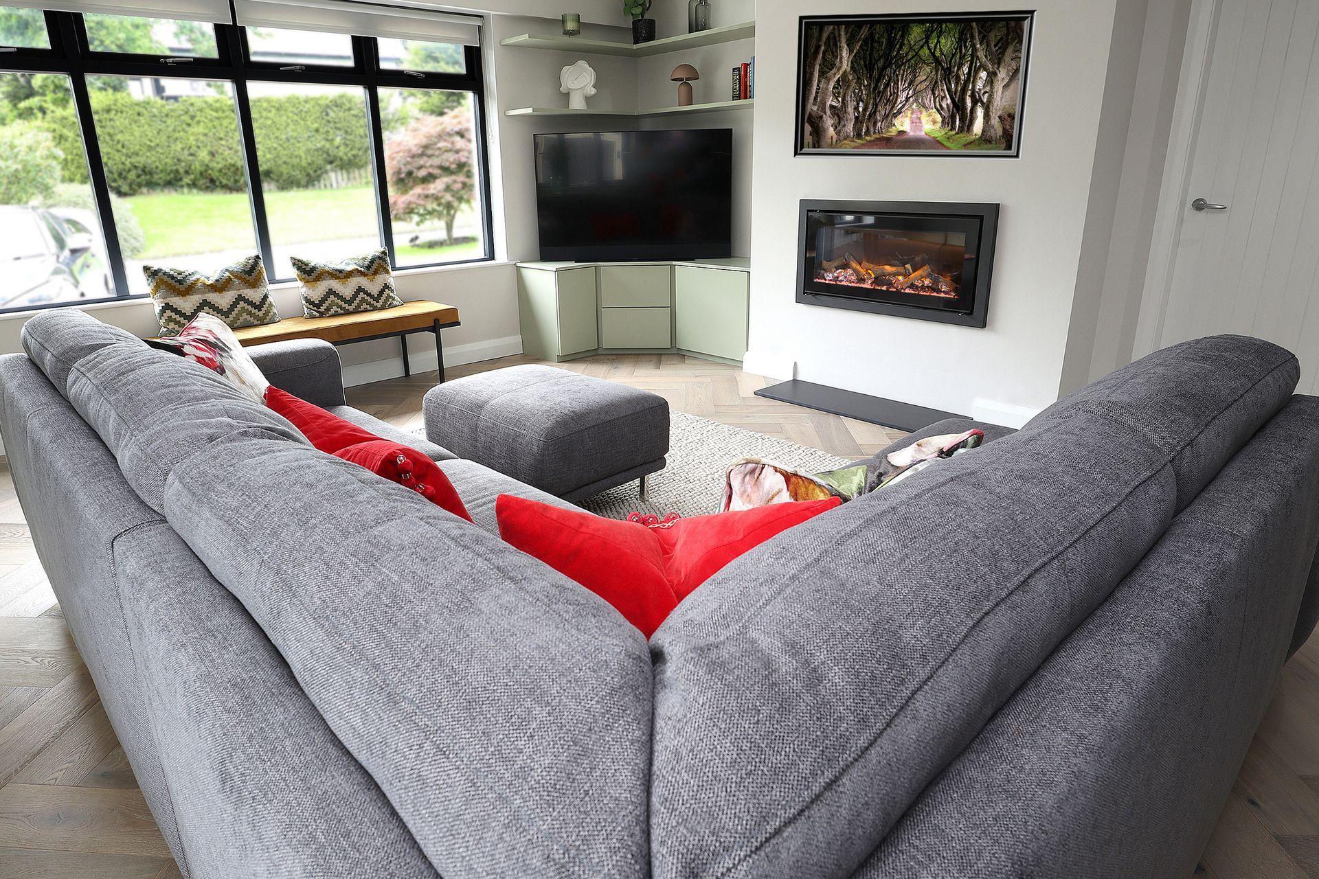 A living room with a couch , ottoman , television and fireplace.