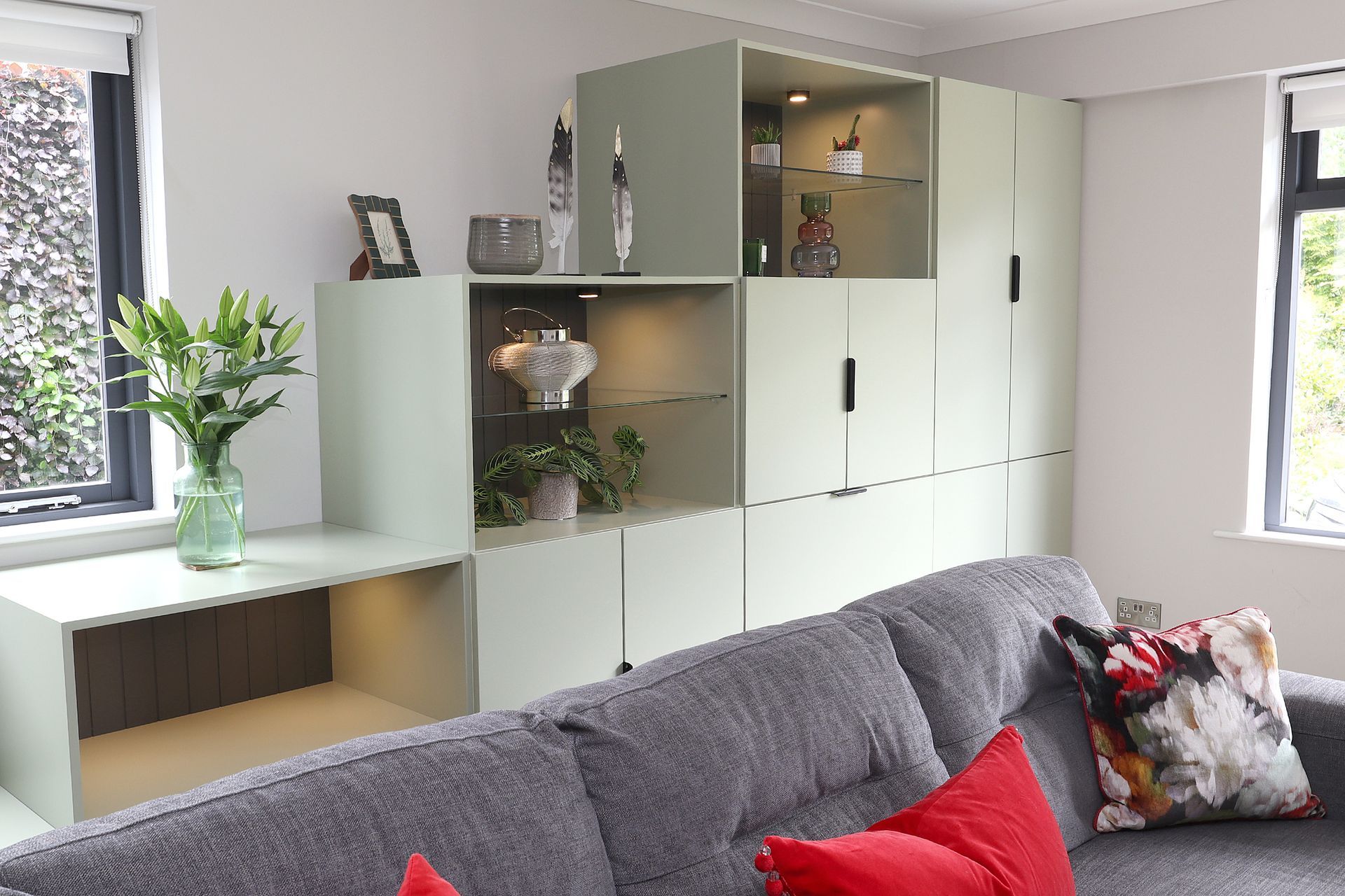 A living room with a couch , cabinets , and a window.