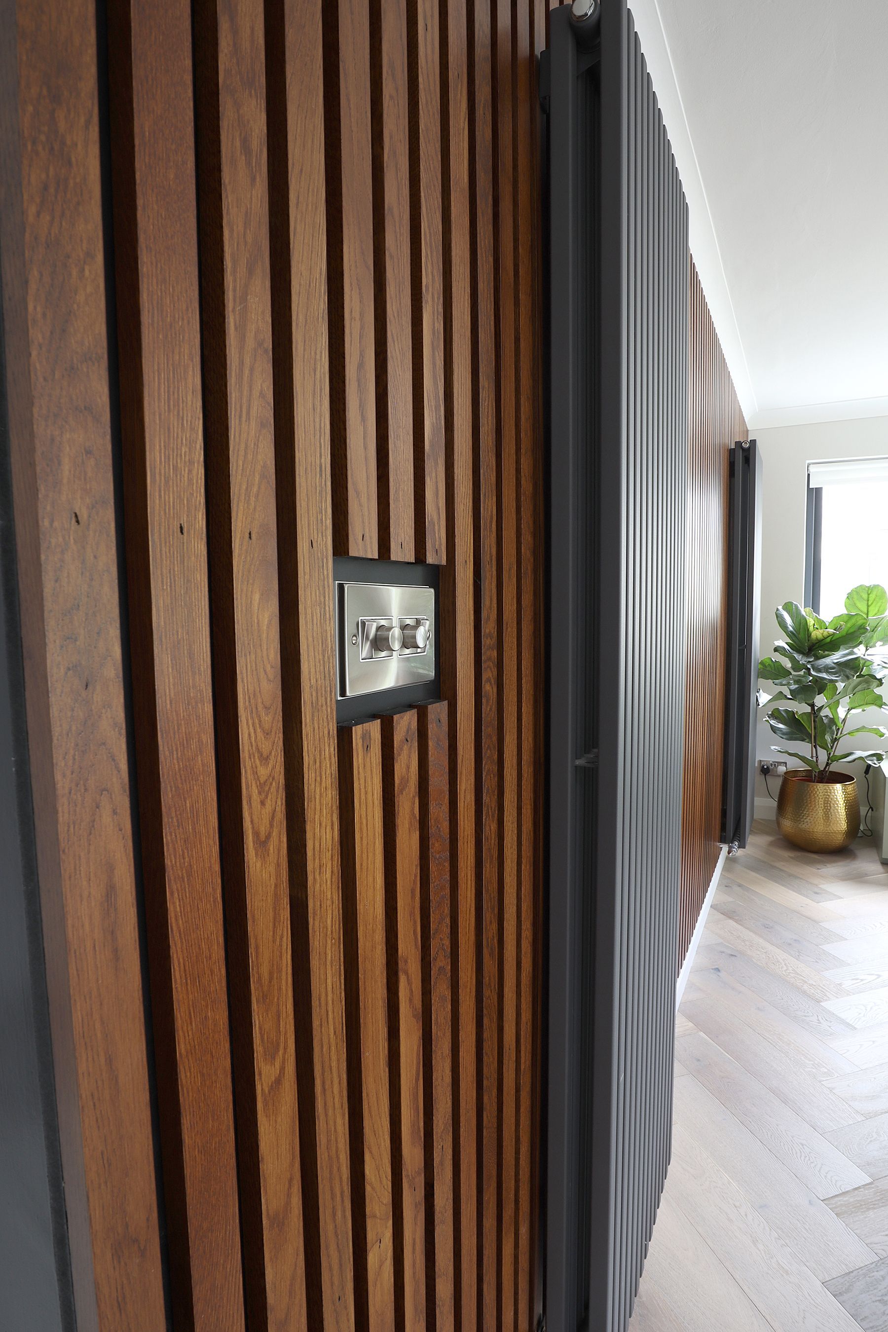 A wooden wall with a light switch on it in a hallway.