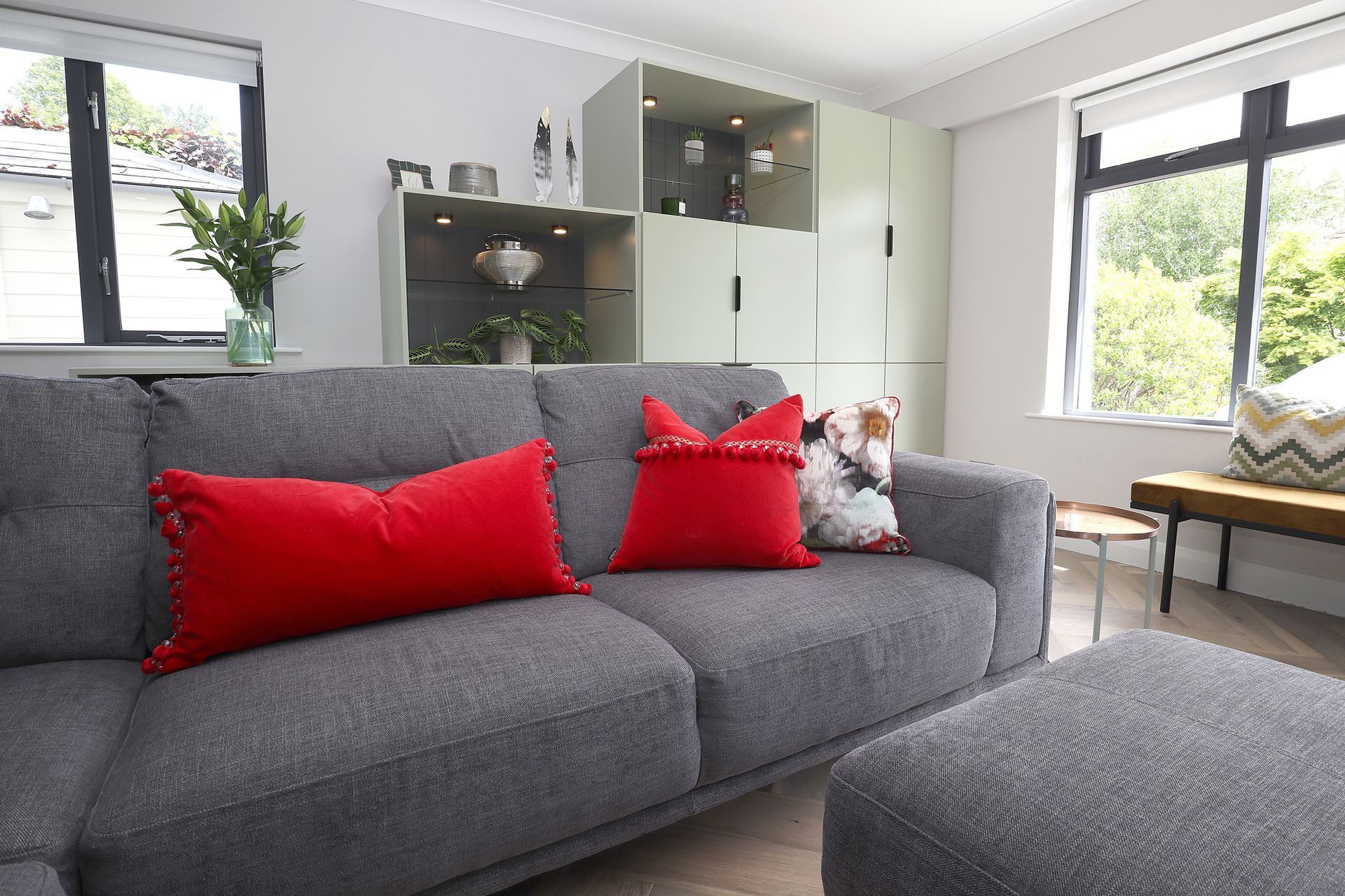 A living room with a grey couch and red pillows