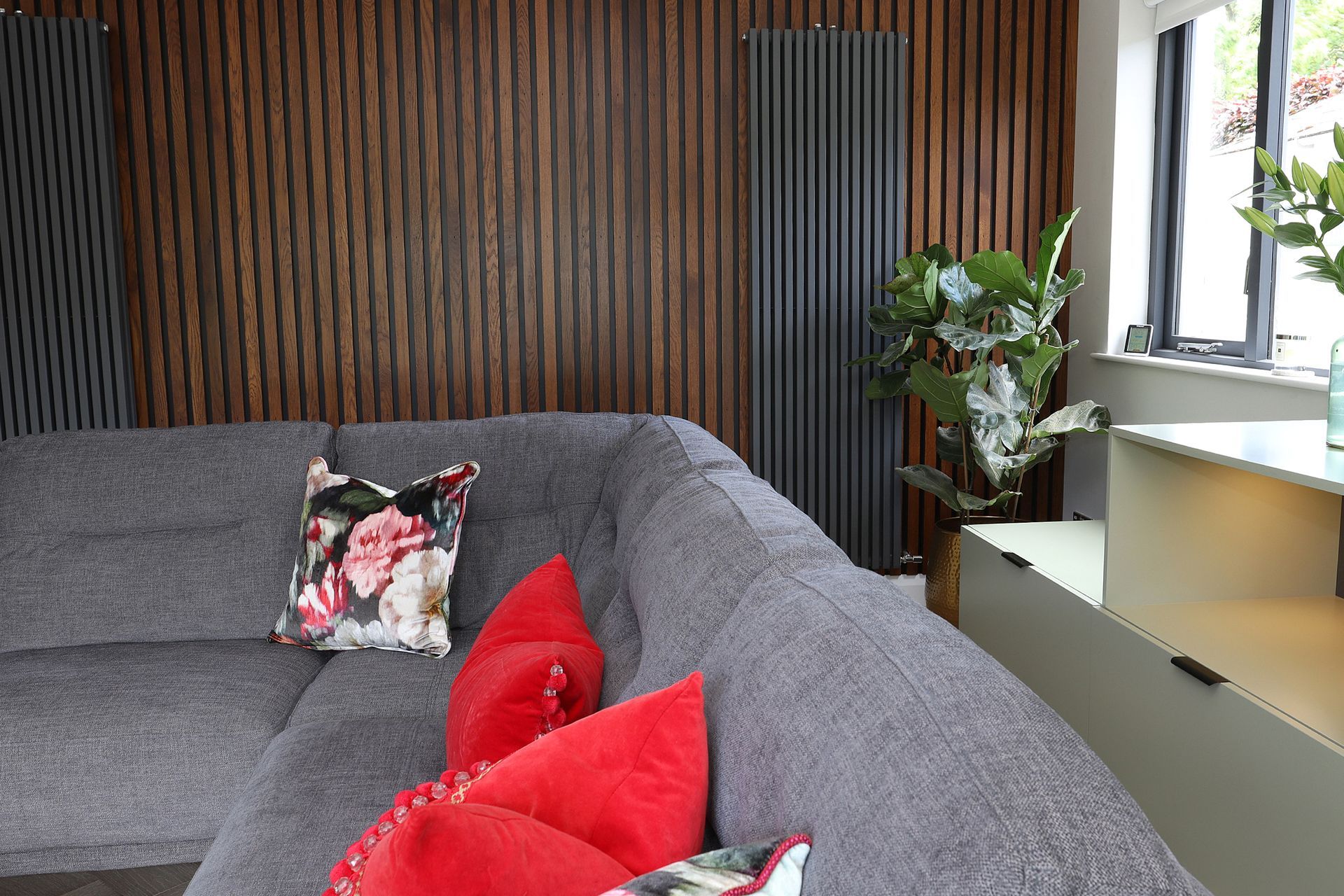 A living room with a gray couch and red pillows.