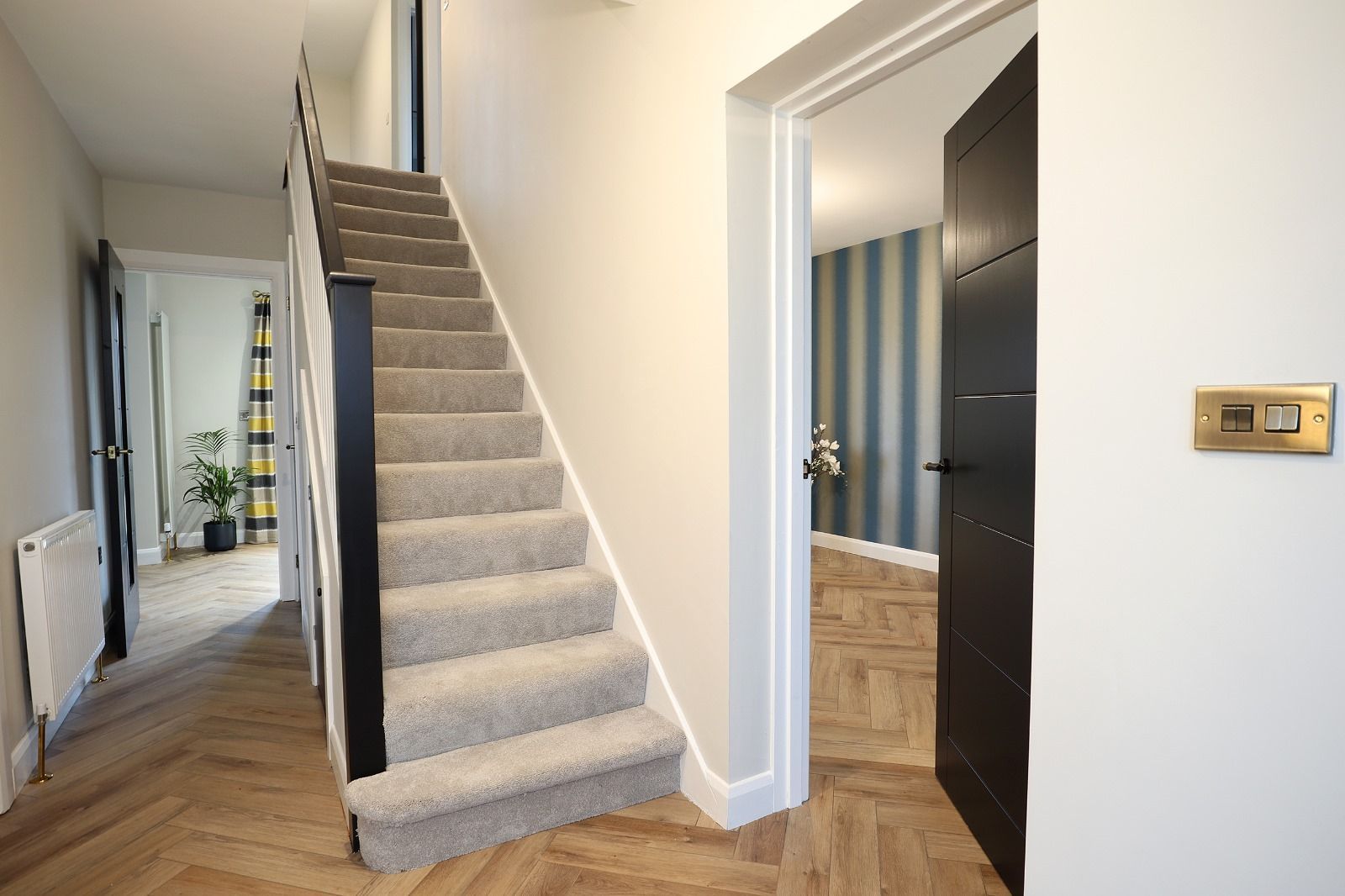 A staircase with a picture on the wall and a lamp on the railing.