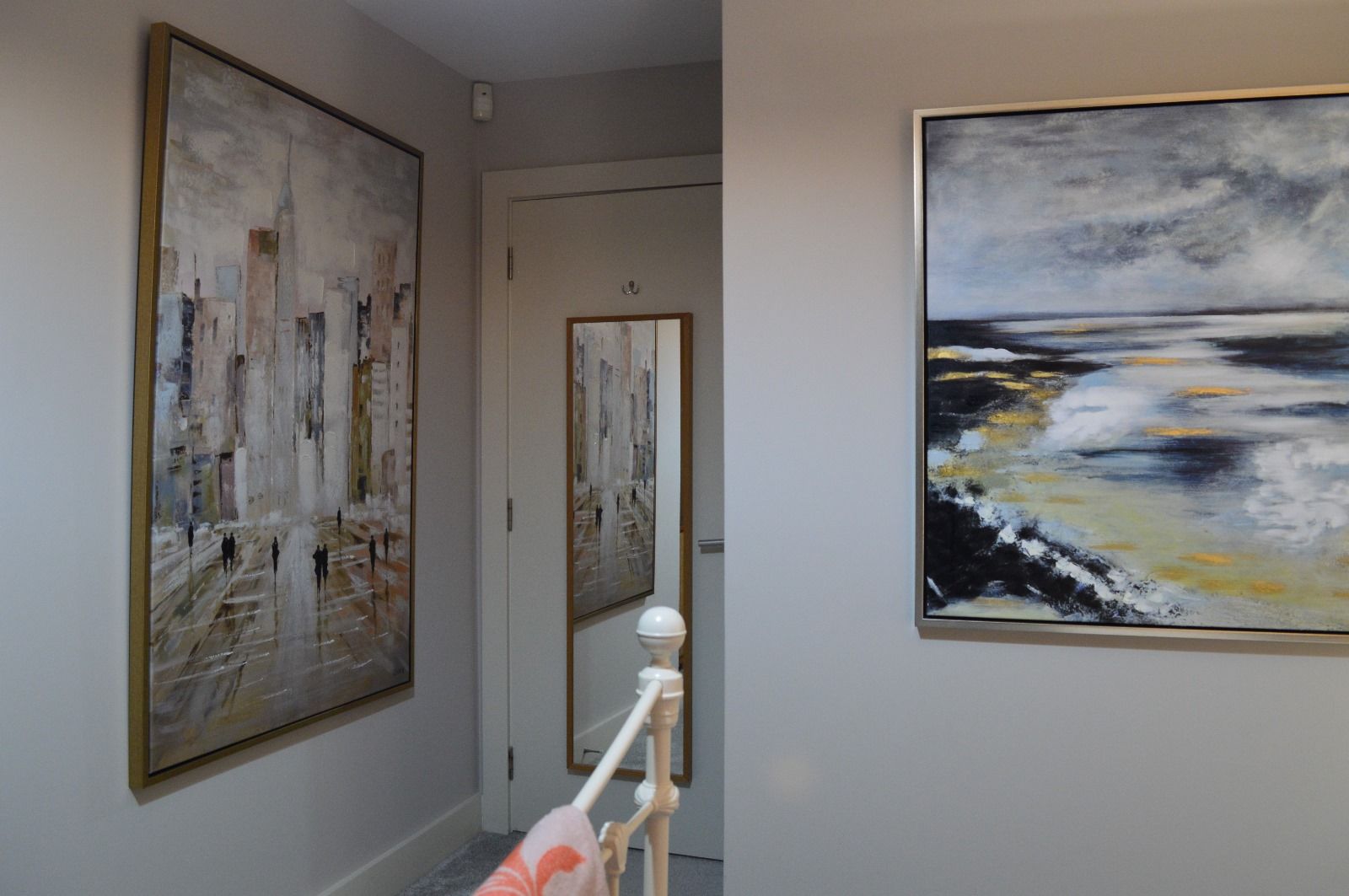 A hallway with two paintings on the wall and a mirror.