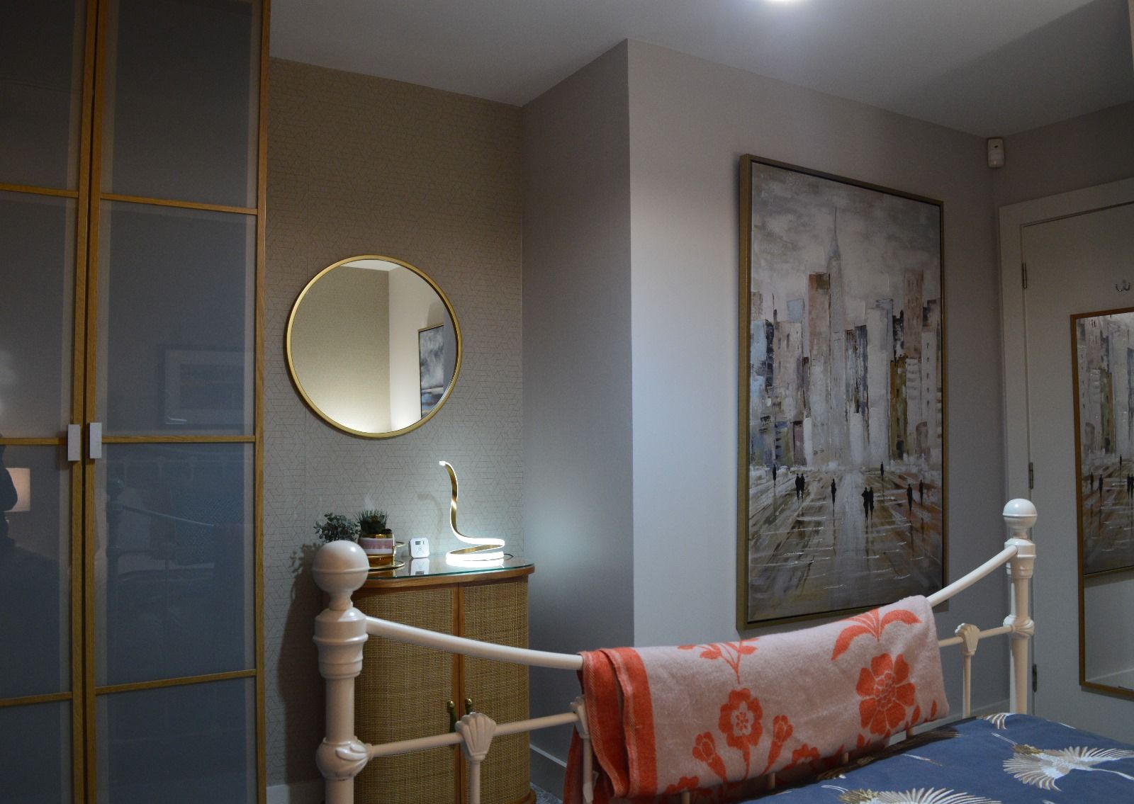 A bedroom with a bed , dresser , mirror and painting on the wall.