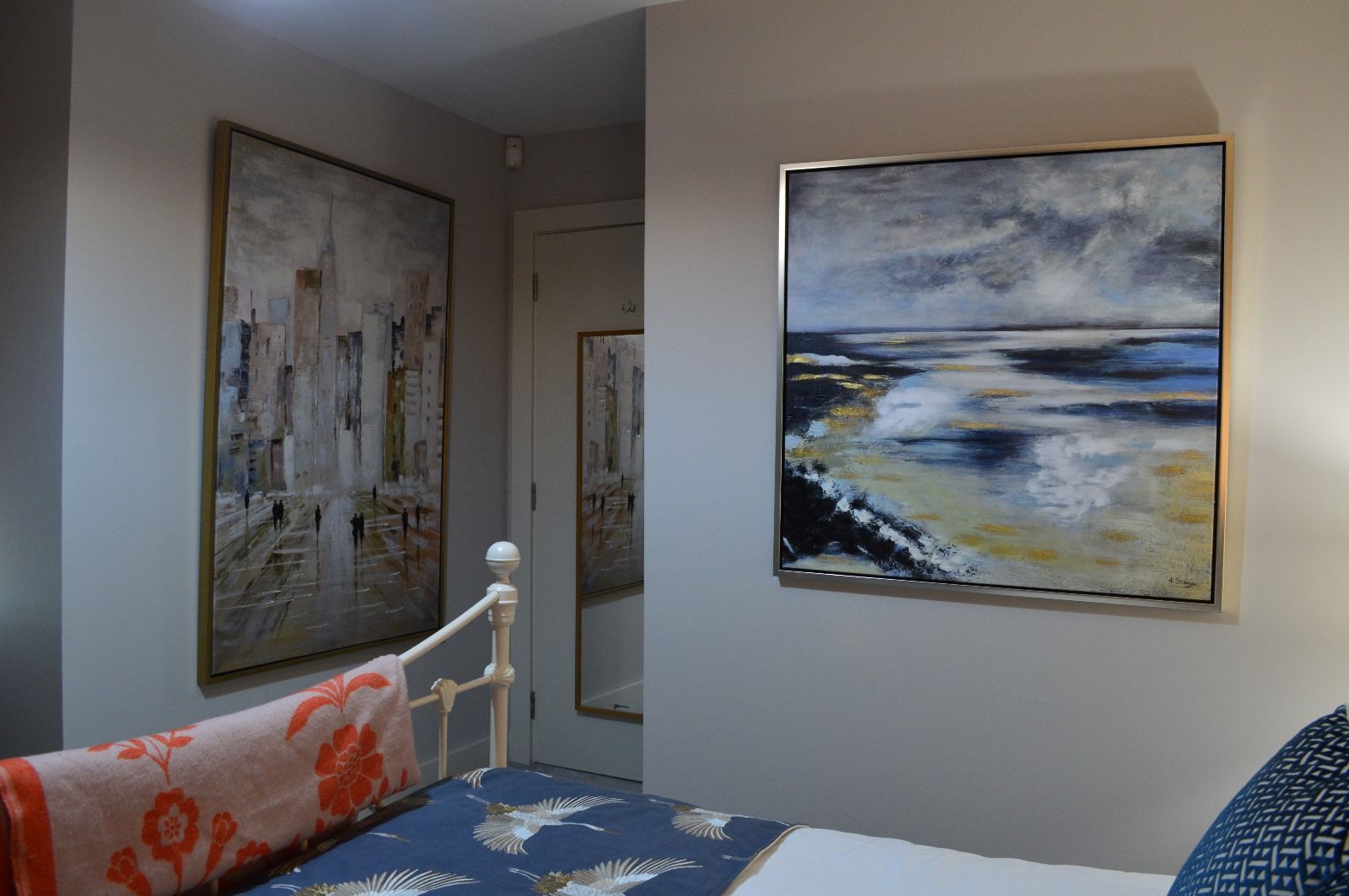 A bedroom with a bed and two paintings on the wall.