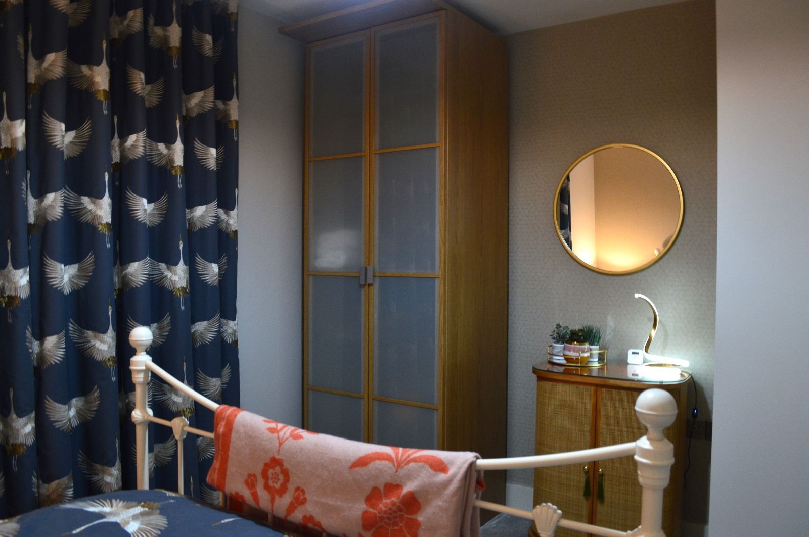 A bedroom with a bed , dresser , mirror and curtains.