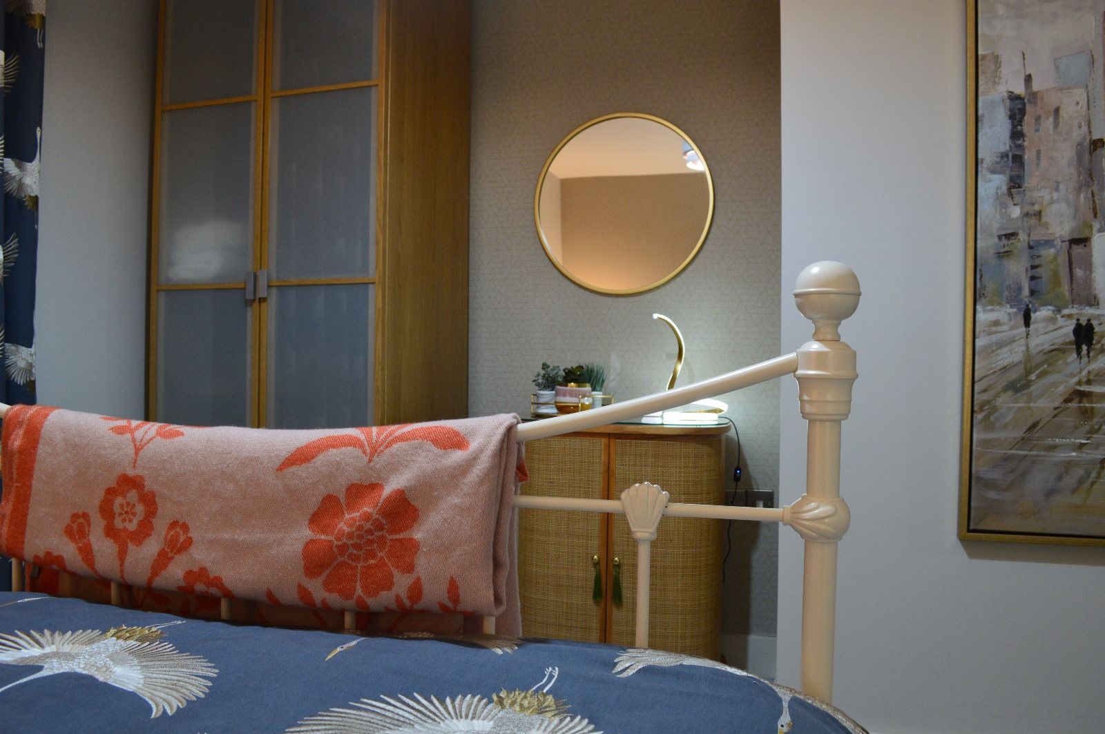 A bedroom with a bed , a mirror , and a painting on the wall.