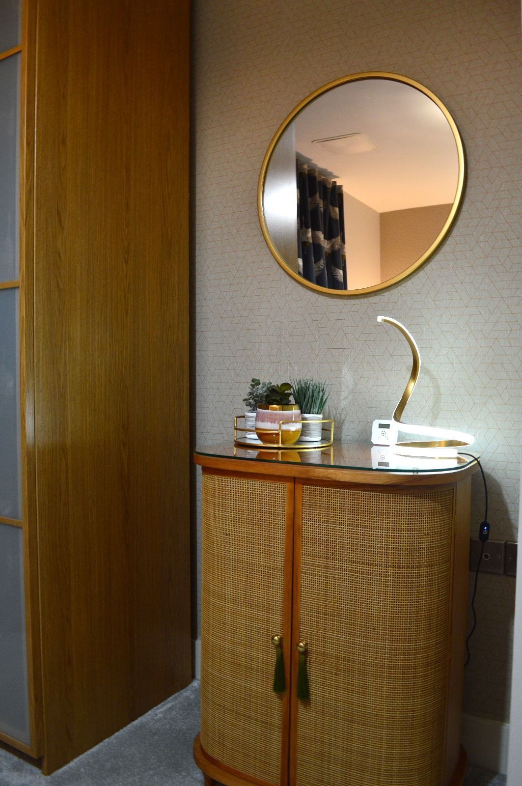 A round mirror is hanging above a wooden cabinet in a room.