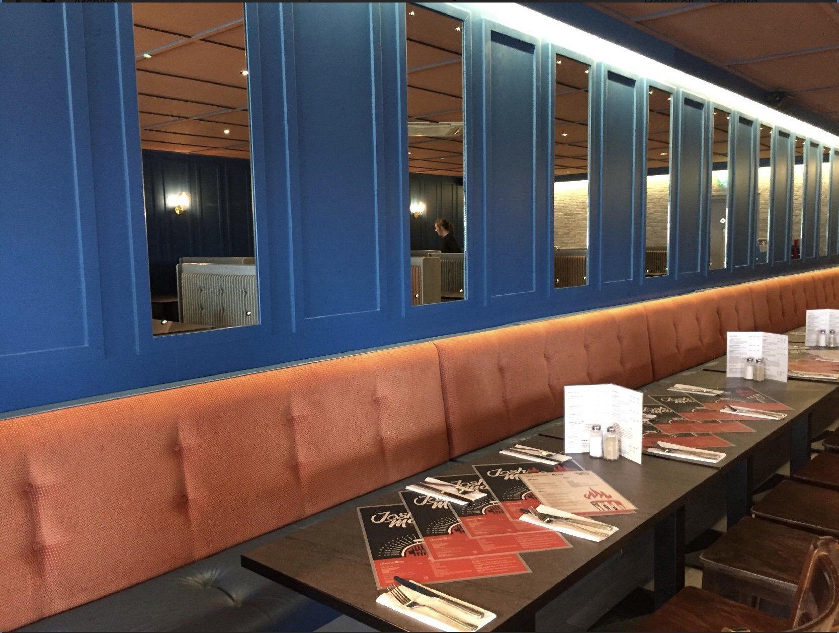 A long row of tables in a restaurant with a blue wall