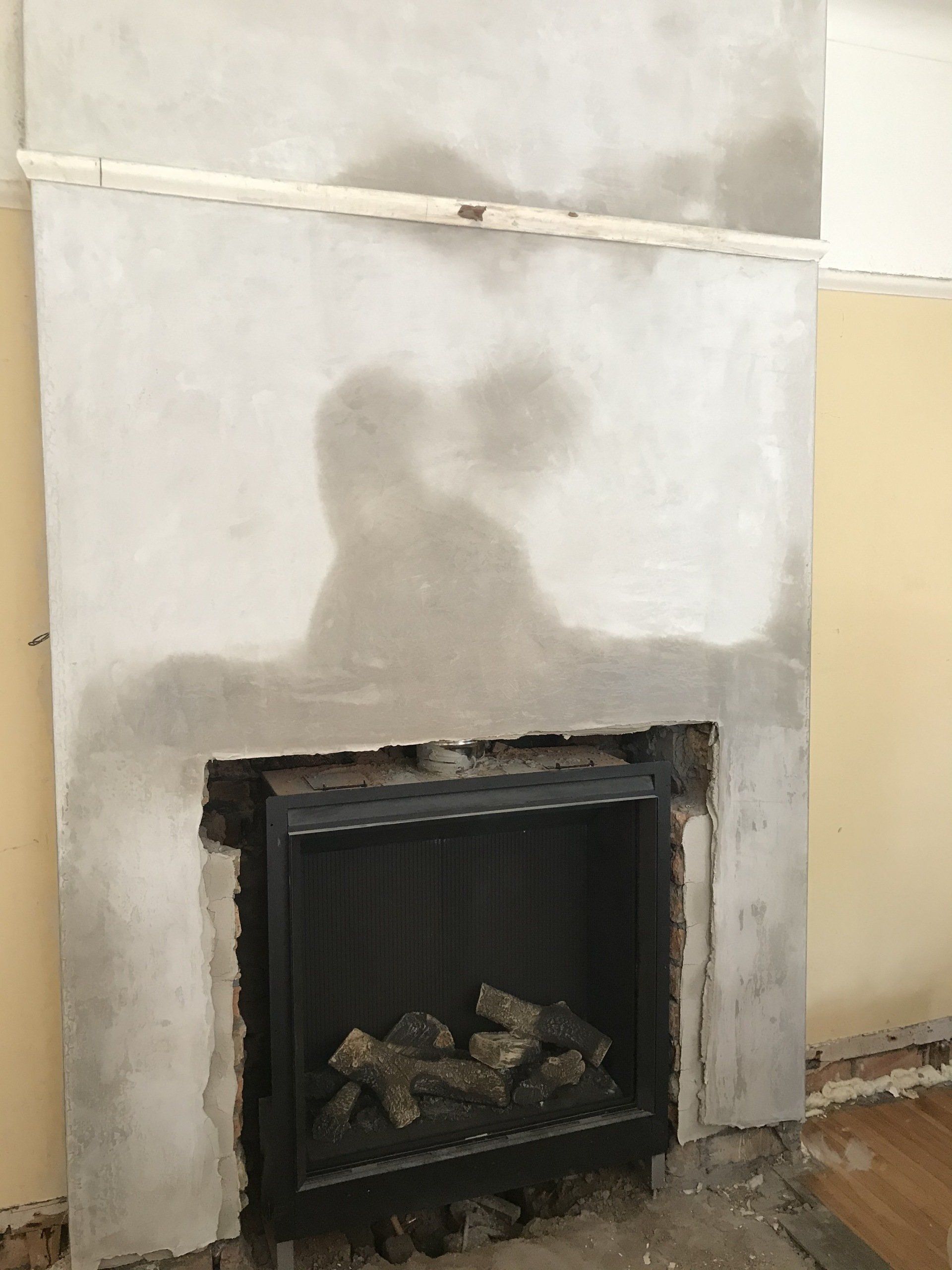 A fireplace with a shadow of a couple kissing on the wall.