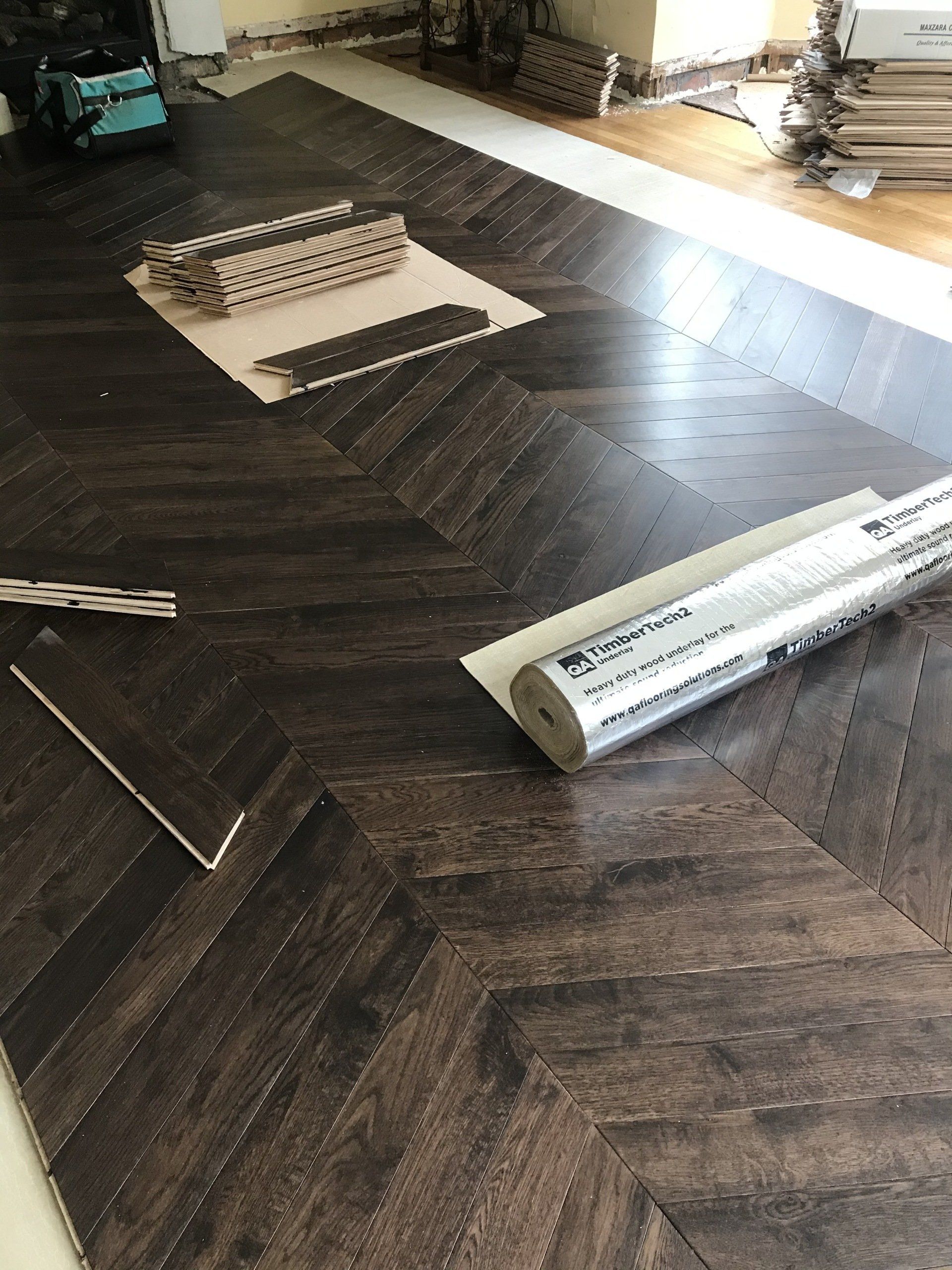 A roll of vinyl flooring is laying on a wooden floor.