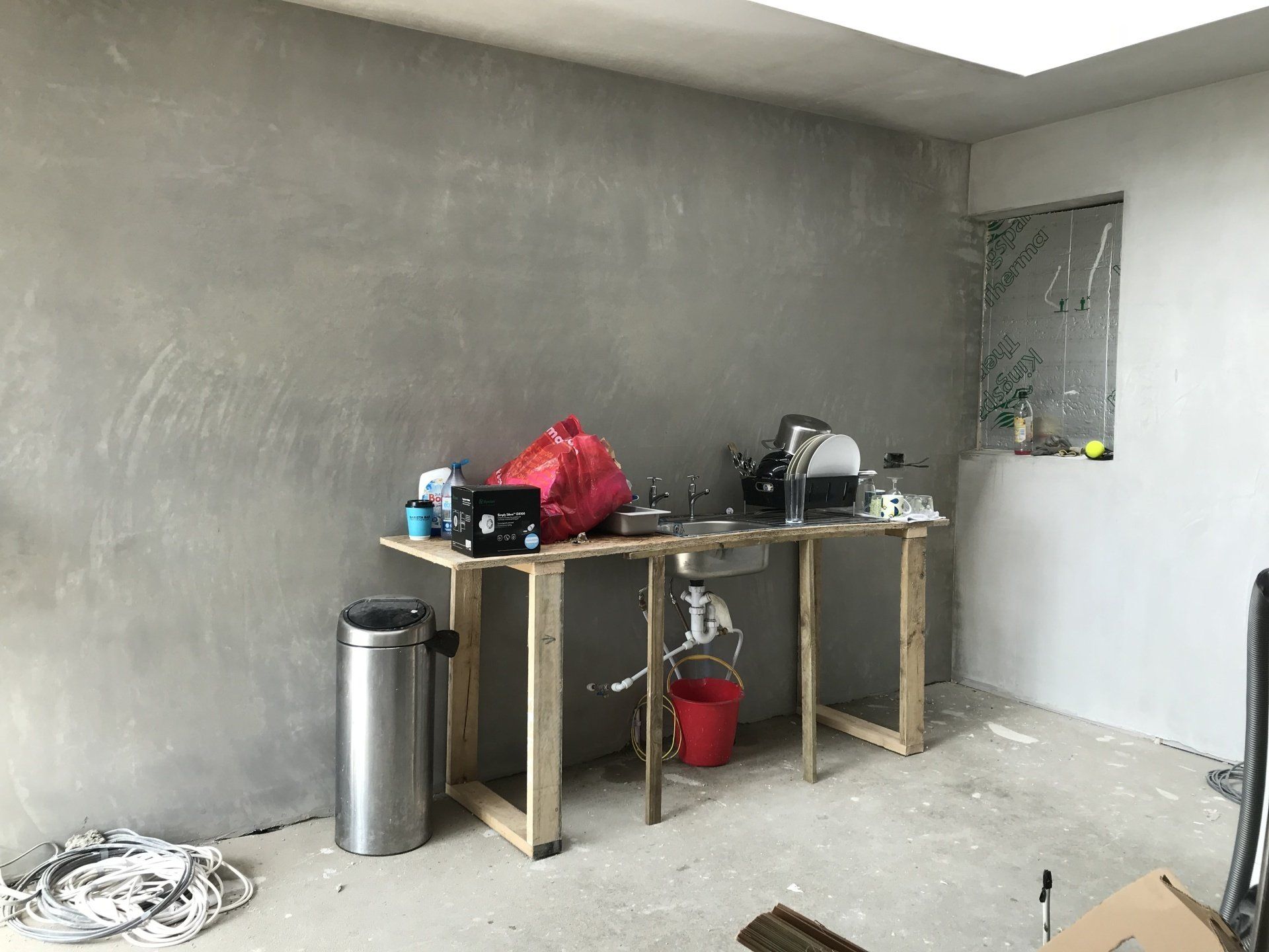 A room with a table and a trash can in it.