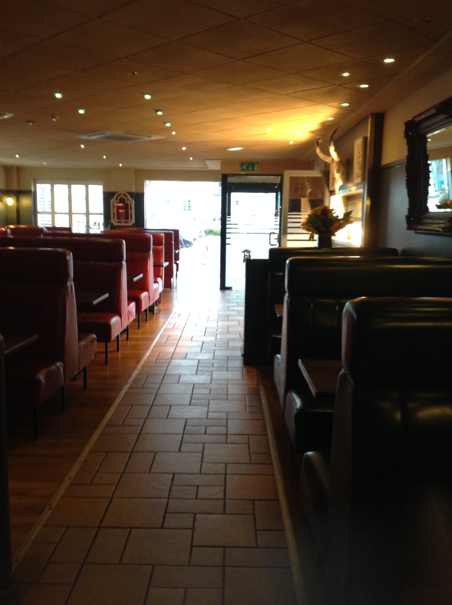 A long hallway in a restaurant with booths and tables