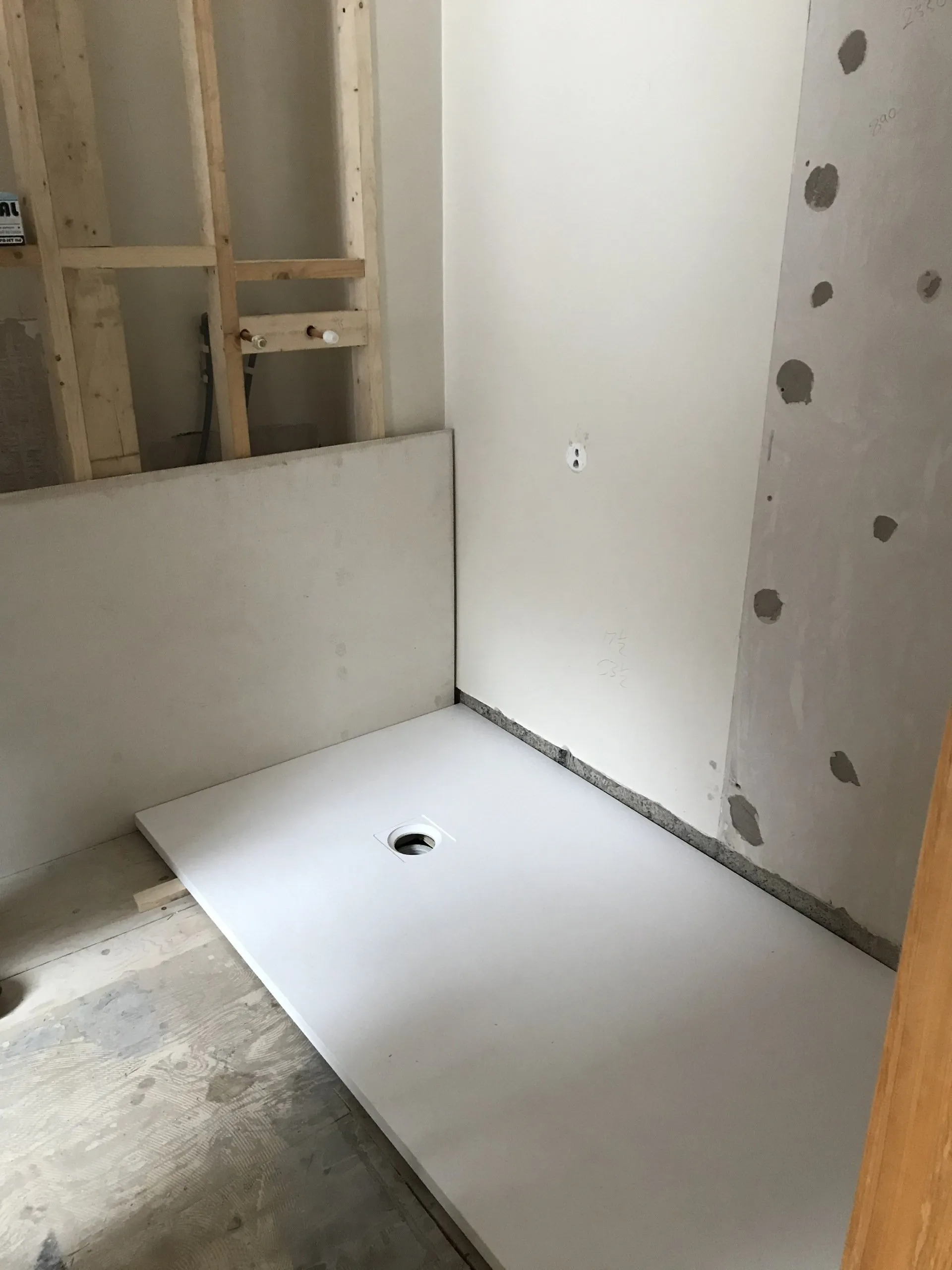 A shower stall is being built in a bathroom under construction.